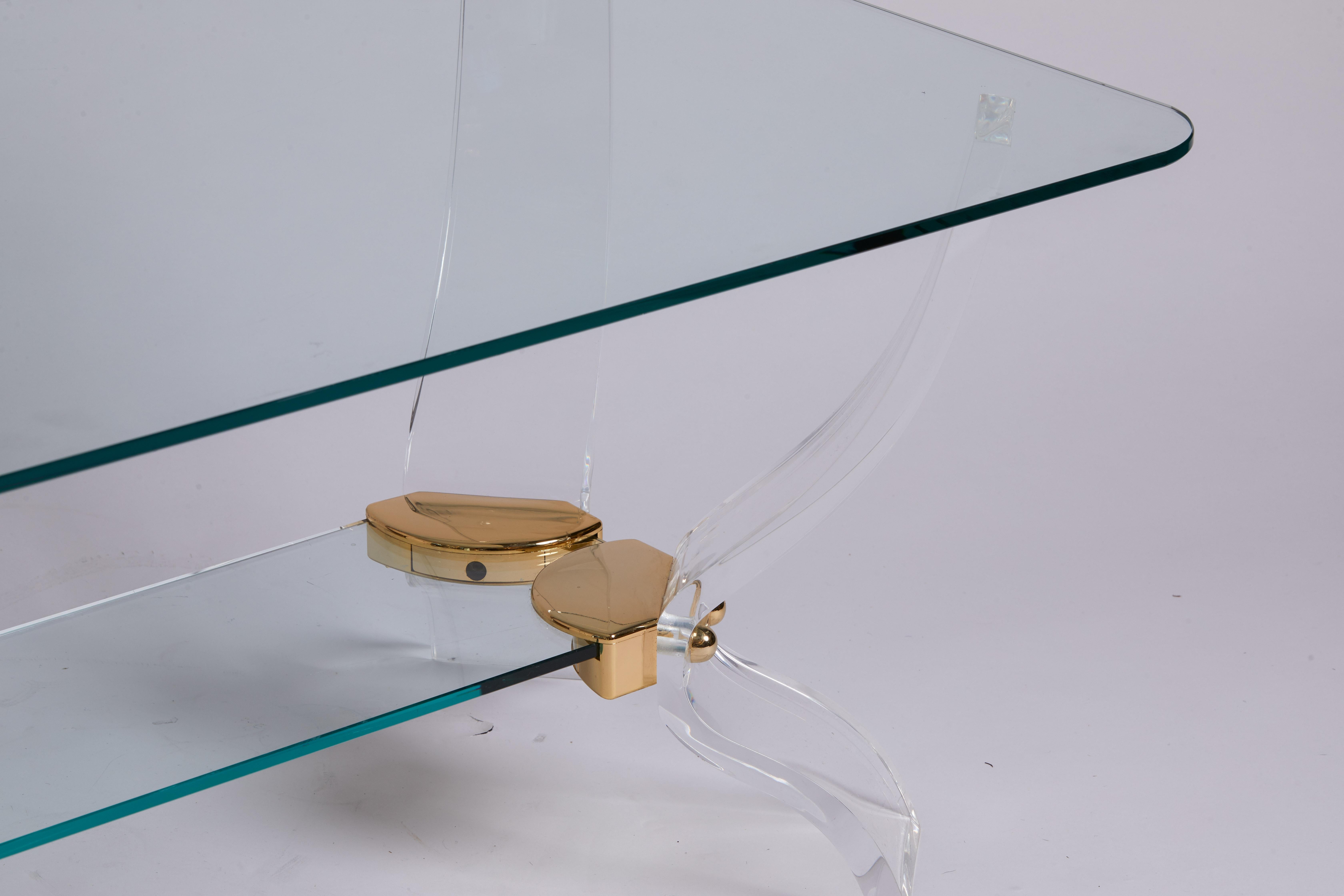 1980s Italian cocktail table made of Lucite legs, glass central portion, and brass accents.