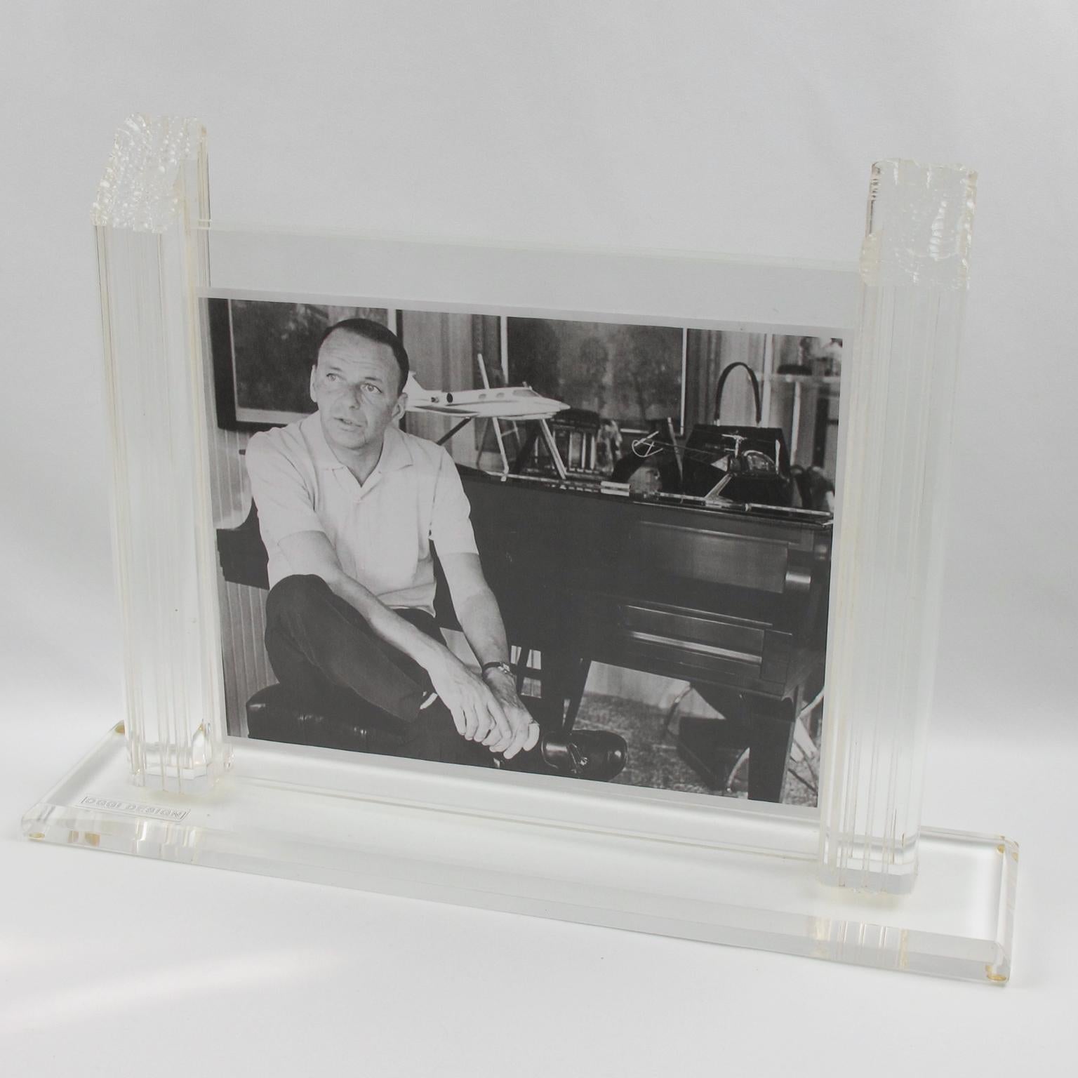 Beautiful modernist Lucite picture photo frame designed by Oggi design, Italy. Large and thick crystal clear Lucite base with beveling topped with carved pole holders finished with an unusual rough carving on top. Two sheets of acrylic to hold the