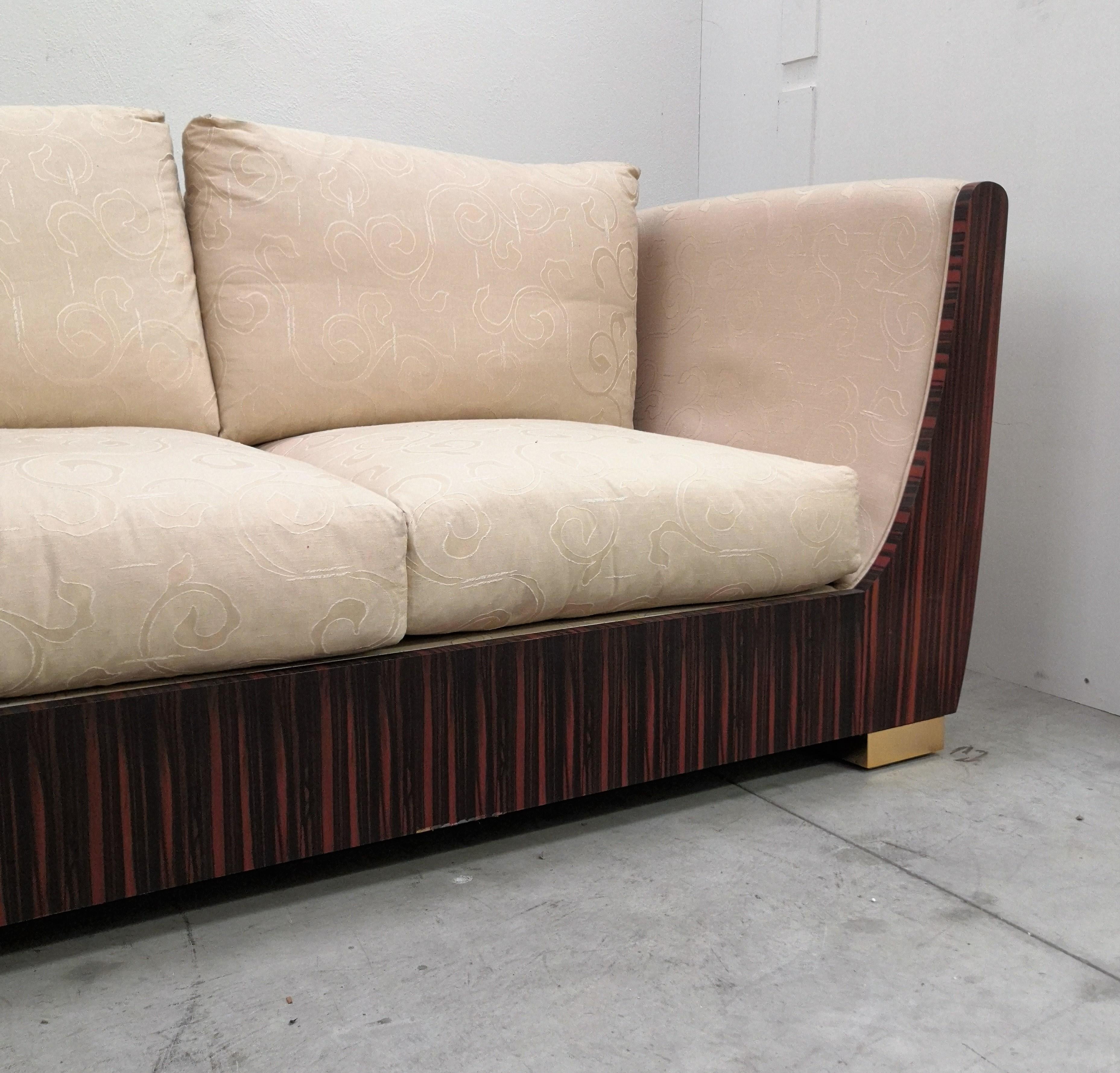 Beautiful and stylish Italian Art Deco style Macassar ebony sofa. The cream and beige textiles contrast beautifully with the polished wood and lacquered furniture common to typical Art-Deco design. We do have one piece of the three-seat version