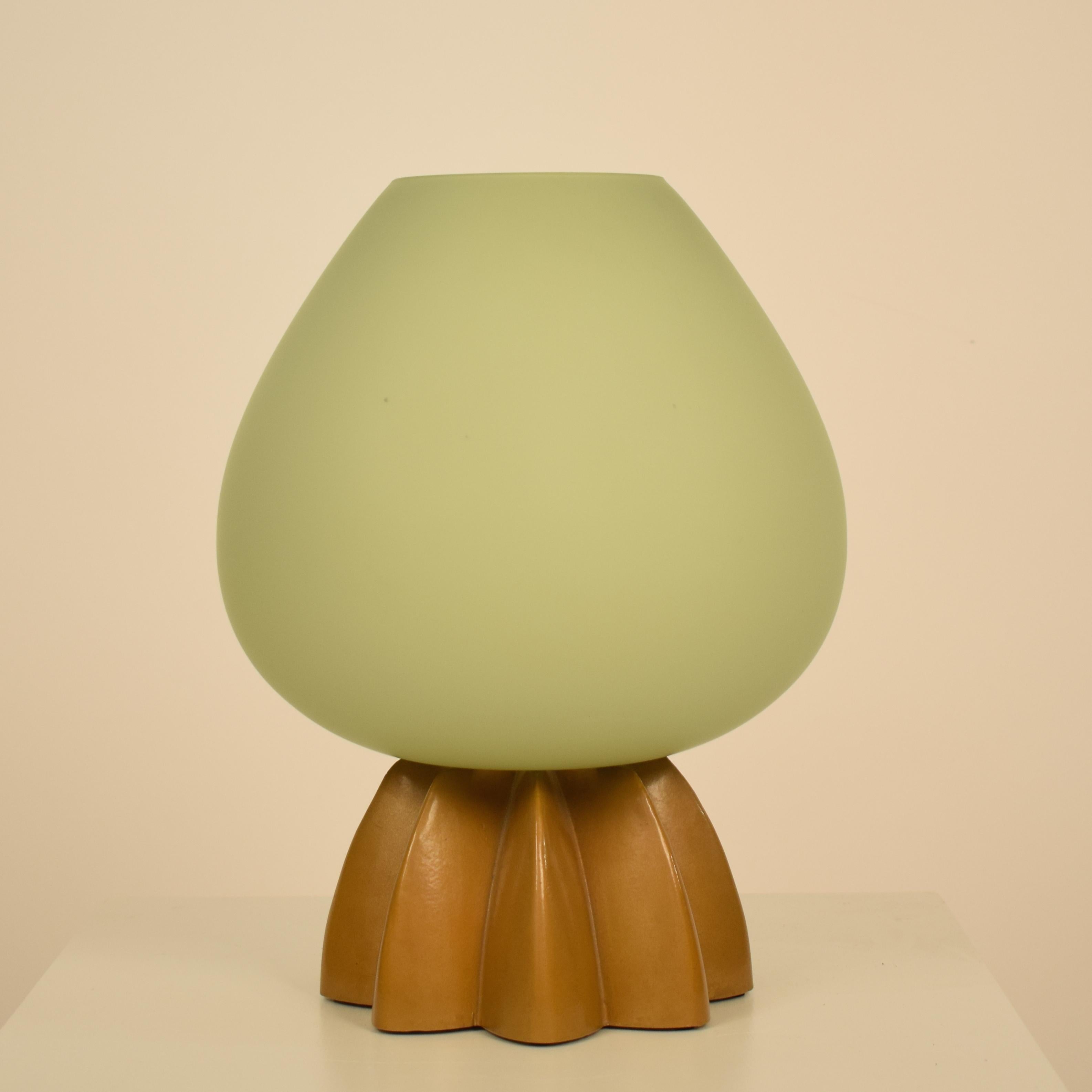 This beautiful 1980s Italian Memphis style table lamp is made out of Murano glass and the base is lacquered metal.
The Murano glass is light green and shines golden when it is lighted.
The base made out metal and lacquered gold.
A unique piece which