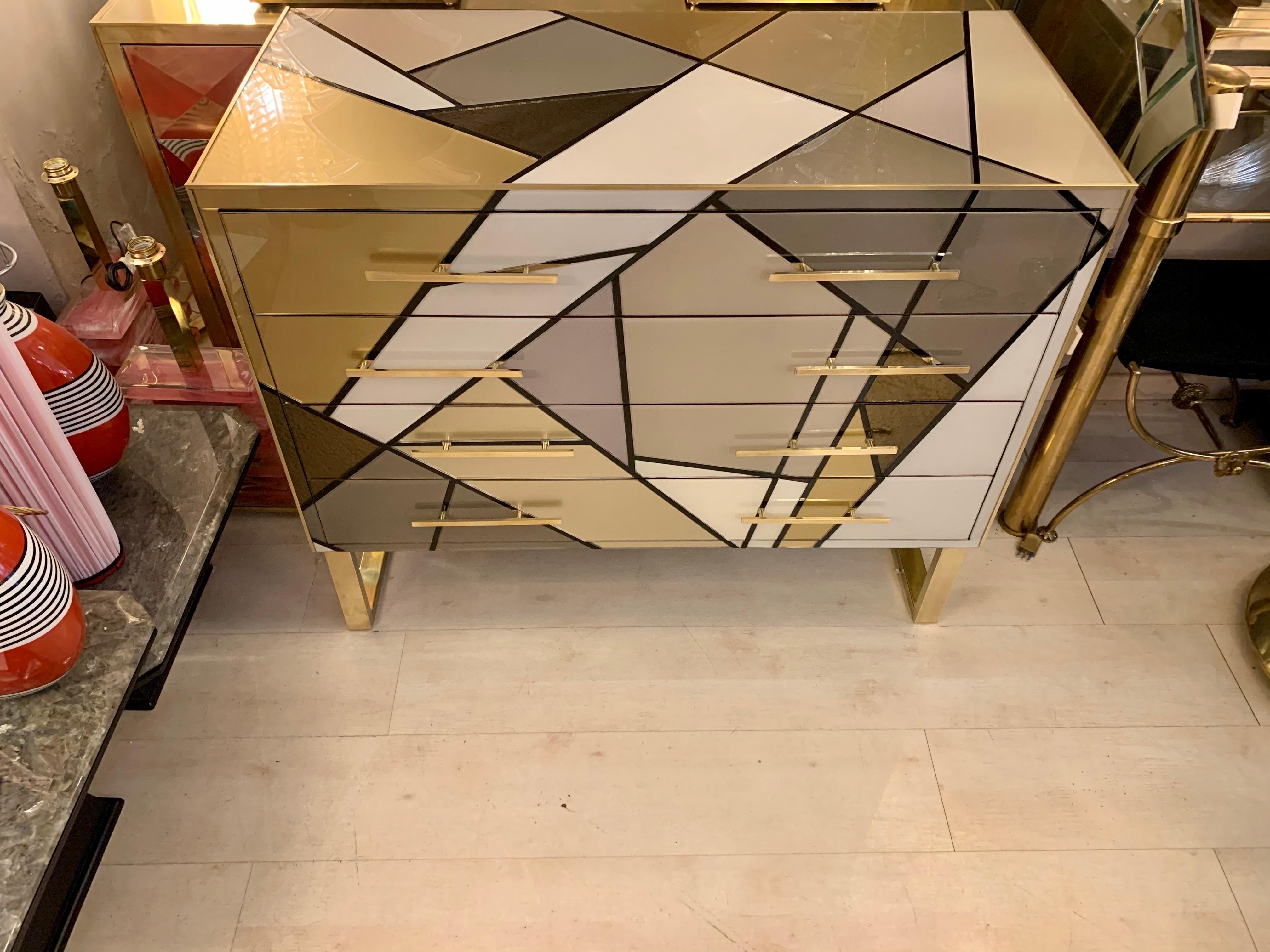 Italian chest of drawers entirely covered with multicolored opaline glass (gold, bronze, ivory, gray, dove gray) in a geometric design on the front, on the top and on the sides.
The chest of drawers has four drawers, brass legs, brass handles and