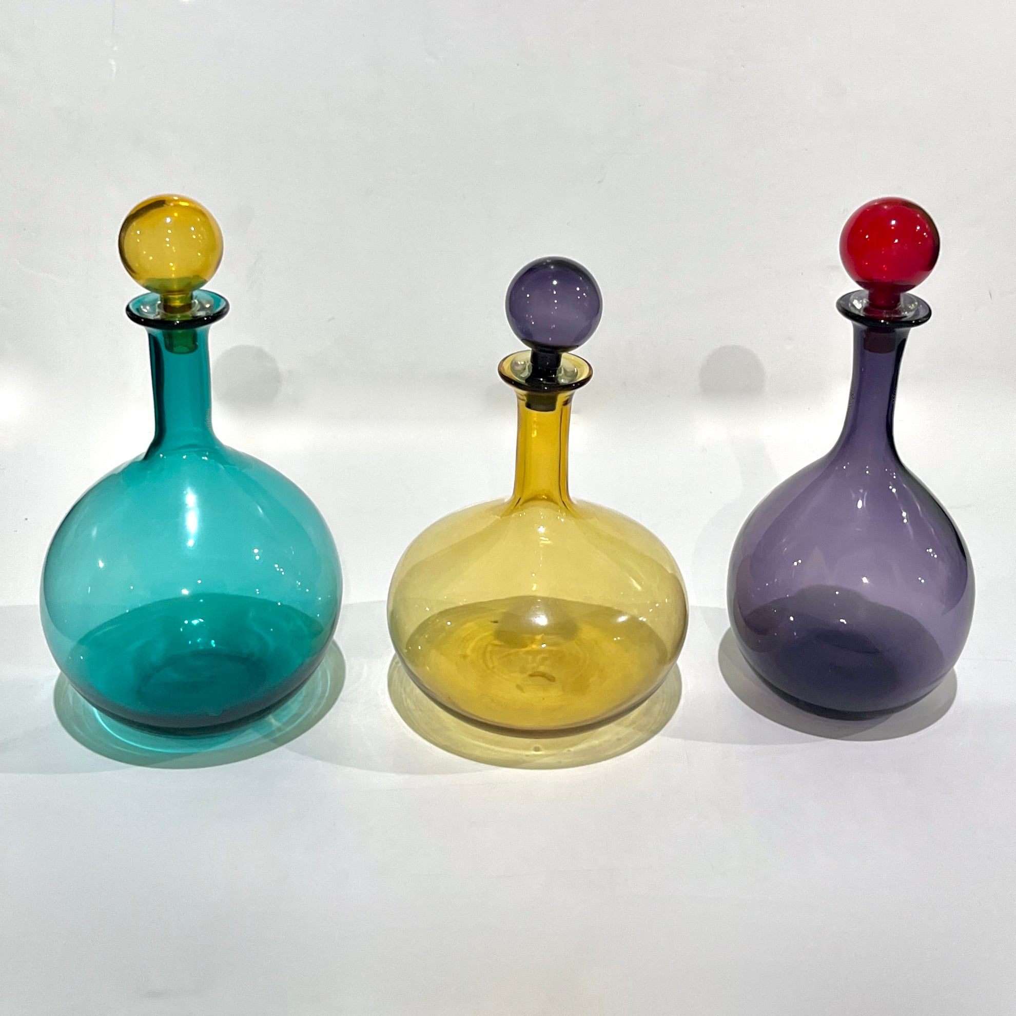 Possono essere acquistate singolarmente - Questo trio post-moderno di bottiglie in vetro soffiato moderno di Murano mostra la magistrale lavorazione colorata ispirata al Design/One e la forma fluida caratteristica dell'arte vetraria italiana della