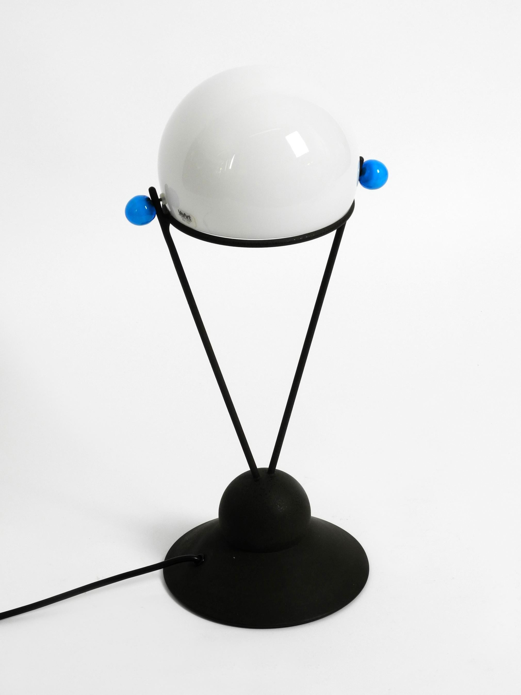 Sehr seltene italienische Tischlampe von VeArt aus den 1980er Jahren mit einem Schirm aus Muranoglas.
Tolles minimalistisches Post Modern Design, handgefertigt.
Der weiße Schirm und die blauen Knöpfe an der Seite sind aus Muranoglas
