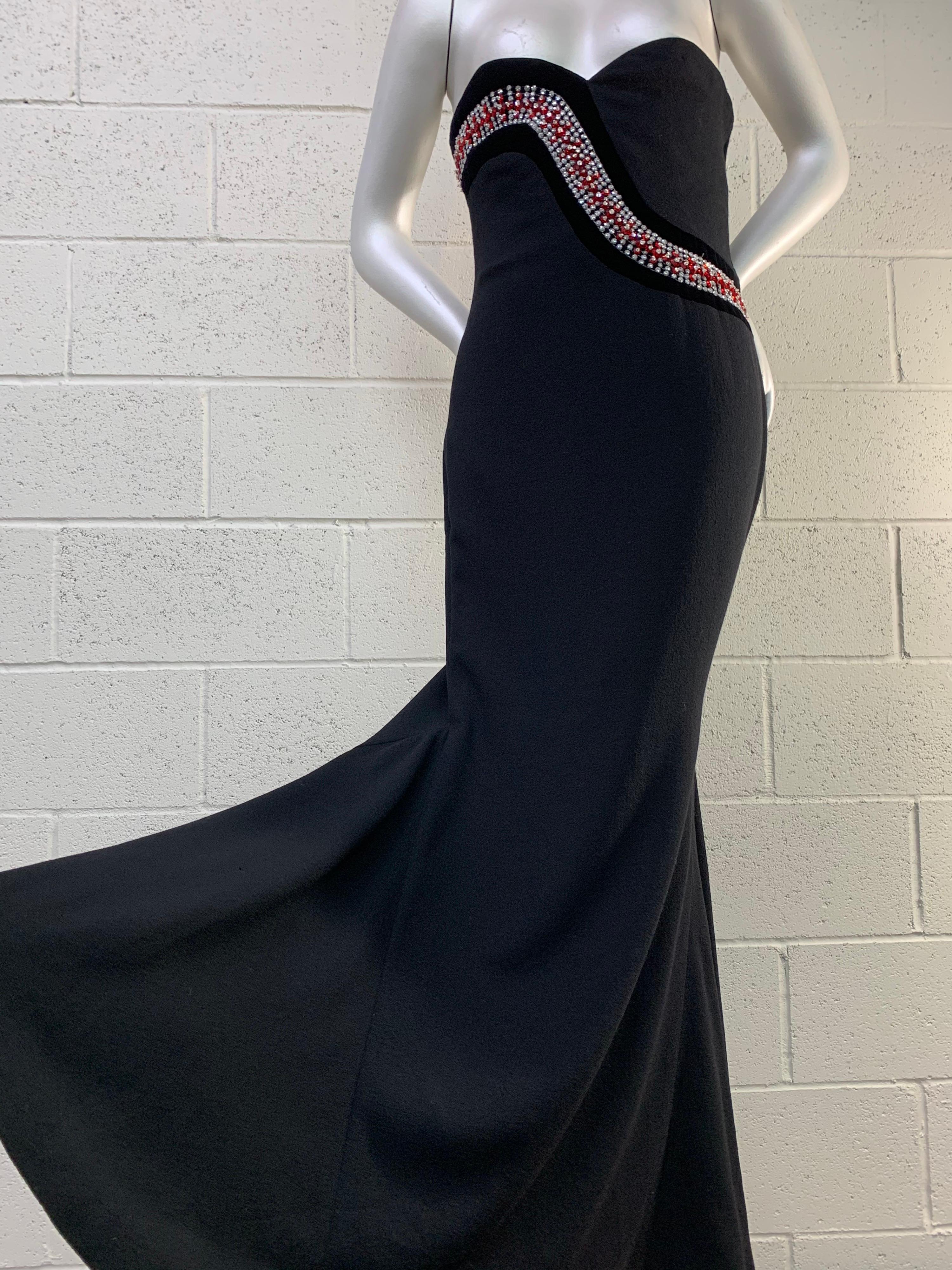 1980s James Galanos Strapless Fishtail Black Wool Crepe Gown w/ Sinuous Crystals: Boned and structured bodice with inner zipper and side closure. Red crystal florals and rhinestones are set on black velvet in a serpentine design encircling the body.