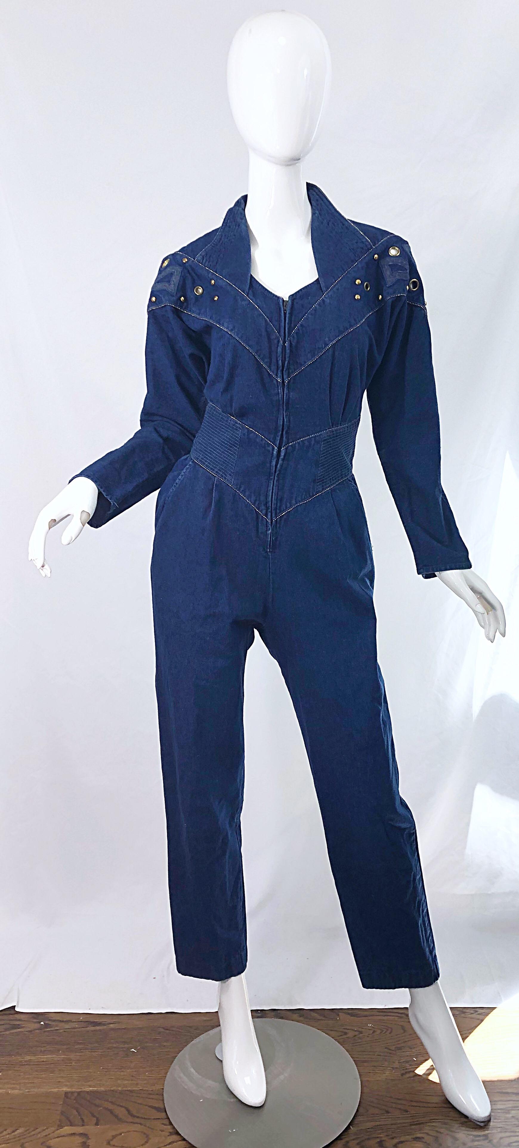 Avant Garde JILLIAN ARTHUR blue jean denim one piece jumpsuit ! Features gold studs and grommets along the front and back dolman sleeve bodice. Hidden zipper up the front. Pockets at each side of the hip. 
Made in USA
Approximately Size Medium /