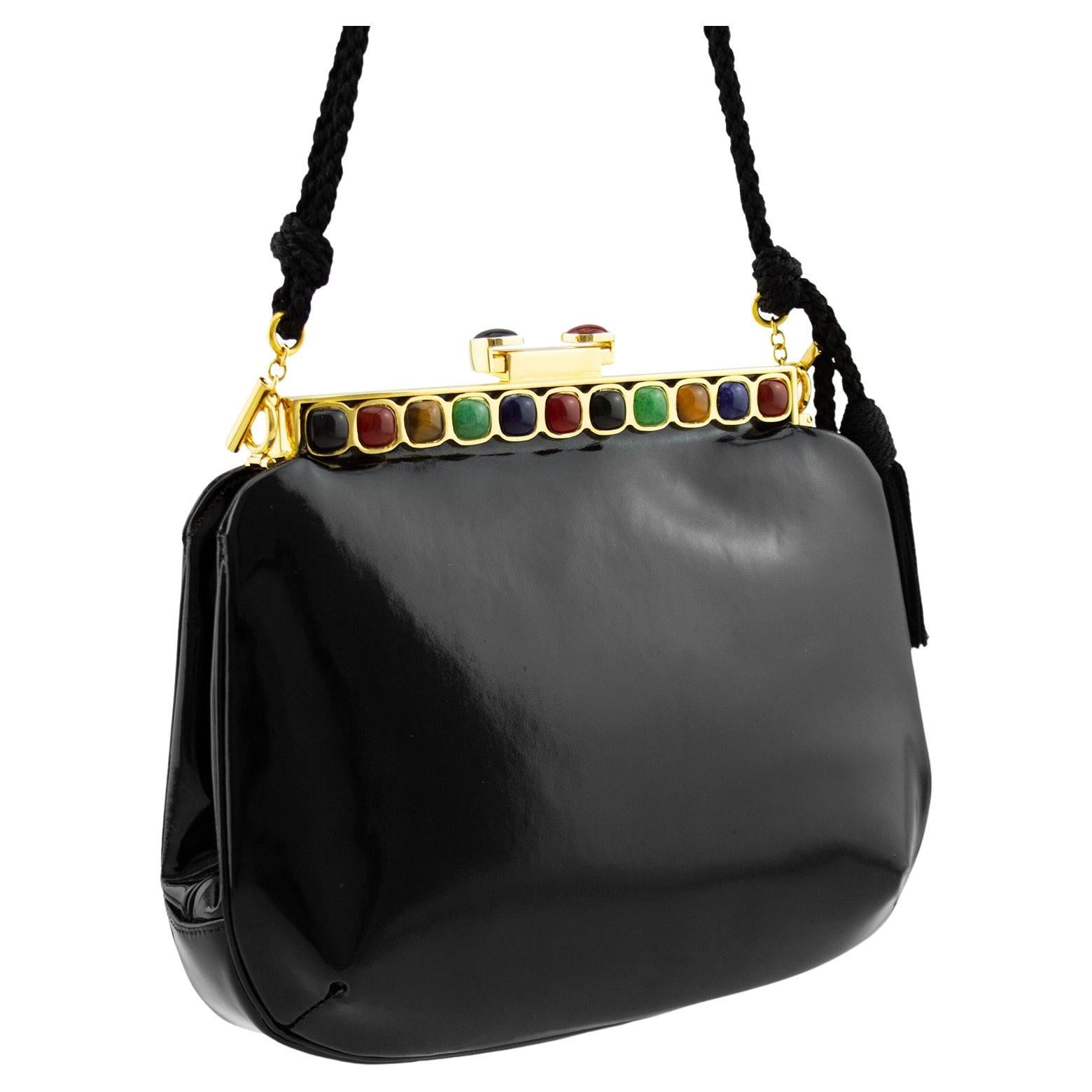 Beautiful Judith Leiber frame style evening bag from the 1980s. Black patent leather with gold tone metal hardware. Frame and sliding clasp are embellished with multi coloured rounded square cabochons. Twisted and knotted long shoulder strap with