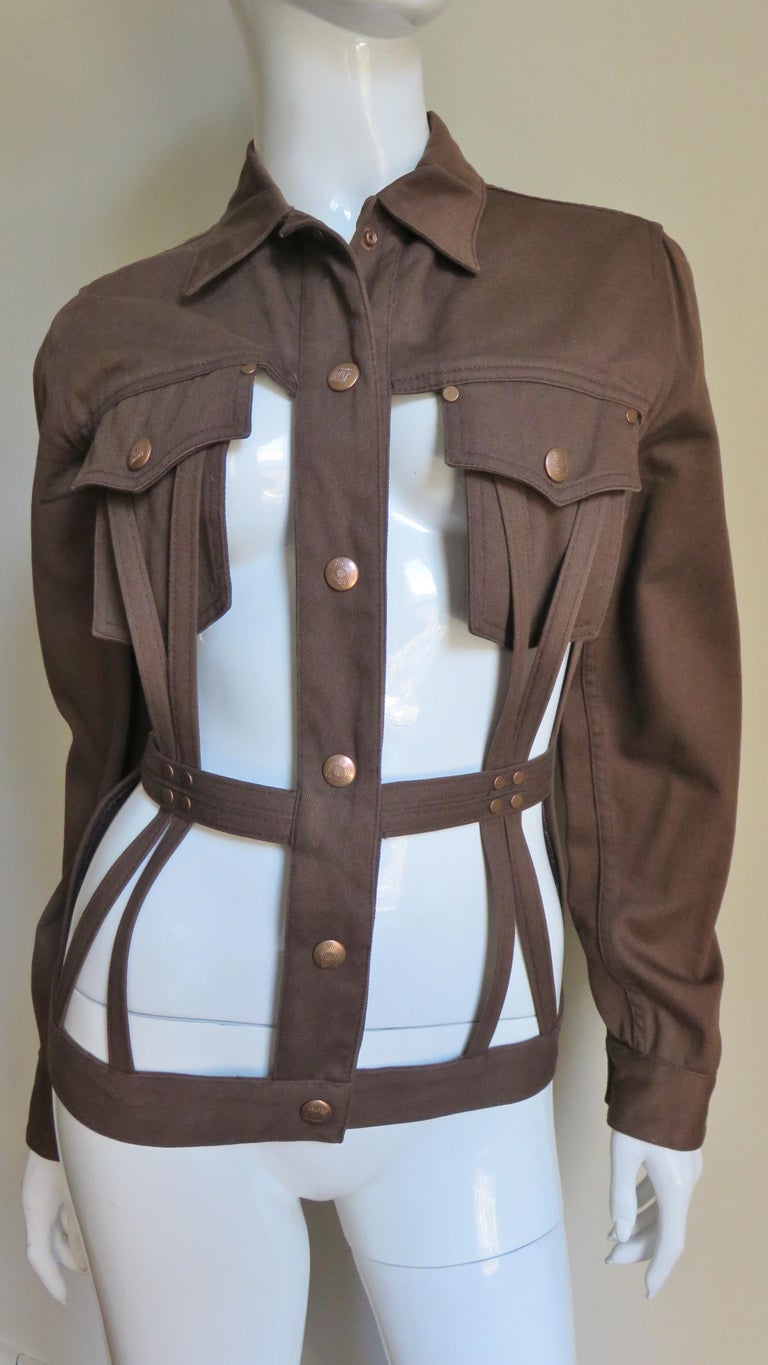 A fabulous brown cotton denim jacket from Jean Paul Gaultier's Junior Gaultier line.  It is a take on the jean jacket with the expected long sleeves, collar, yoke and copper metal snaps closing the front, cuffs and breast pockets.  The dramatic