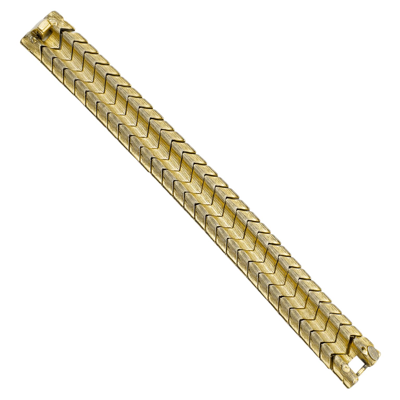 1980s Kenneth Jay Lane statement bracelet. Gold tone metal chevron that is ribbed and put together to look like a woven pattern. 0.75