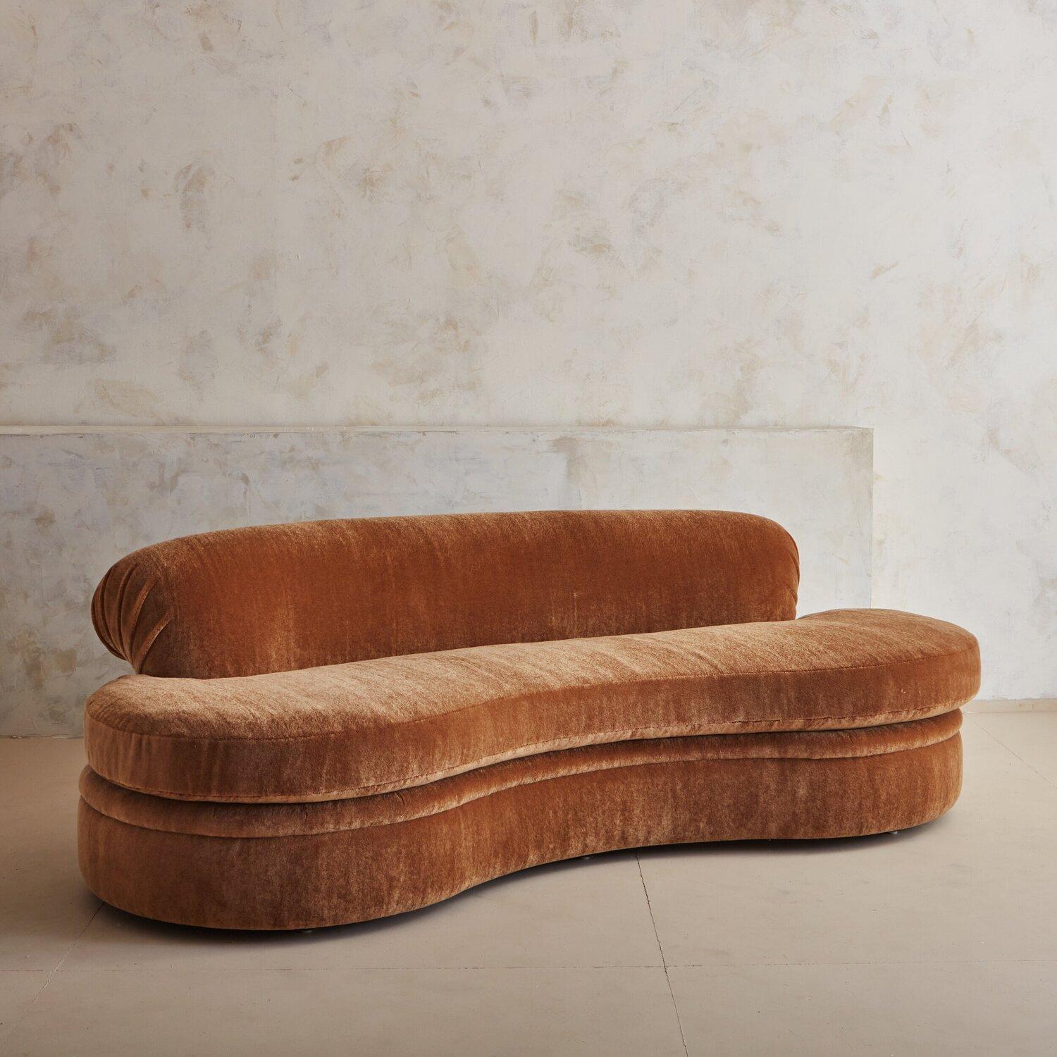 An American made 1980s kidney shaped curved sofa. This exceptionally plush sofa is extra deep, at 45.25 deep and features original down cushions that we refreshed; and a gorgeous Cognac hued mohair with a very thick pile. This piece has been