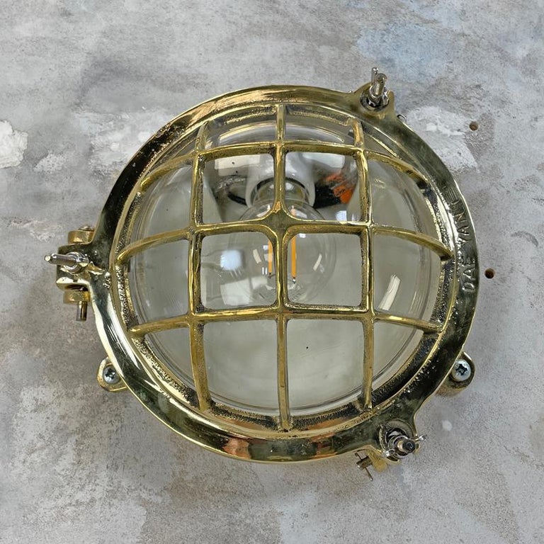 A vintage industrial cast brass circular bulkhead wall light with cast brass cage and glass domed shade.

Originally marine lighting, this type of aluminium circular bulkhead is found on ship passageways. Professionally restored and rewired by
