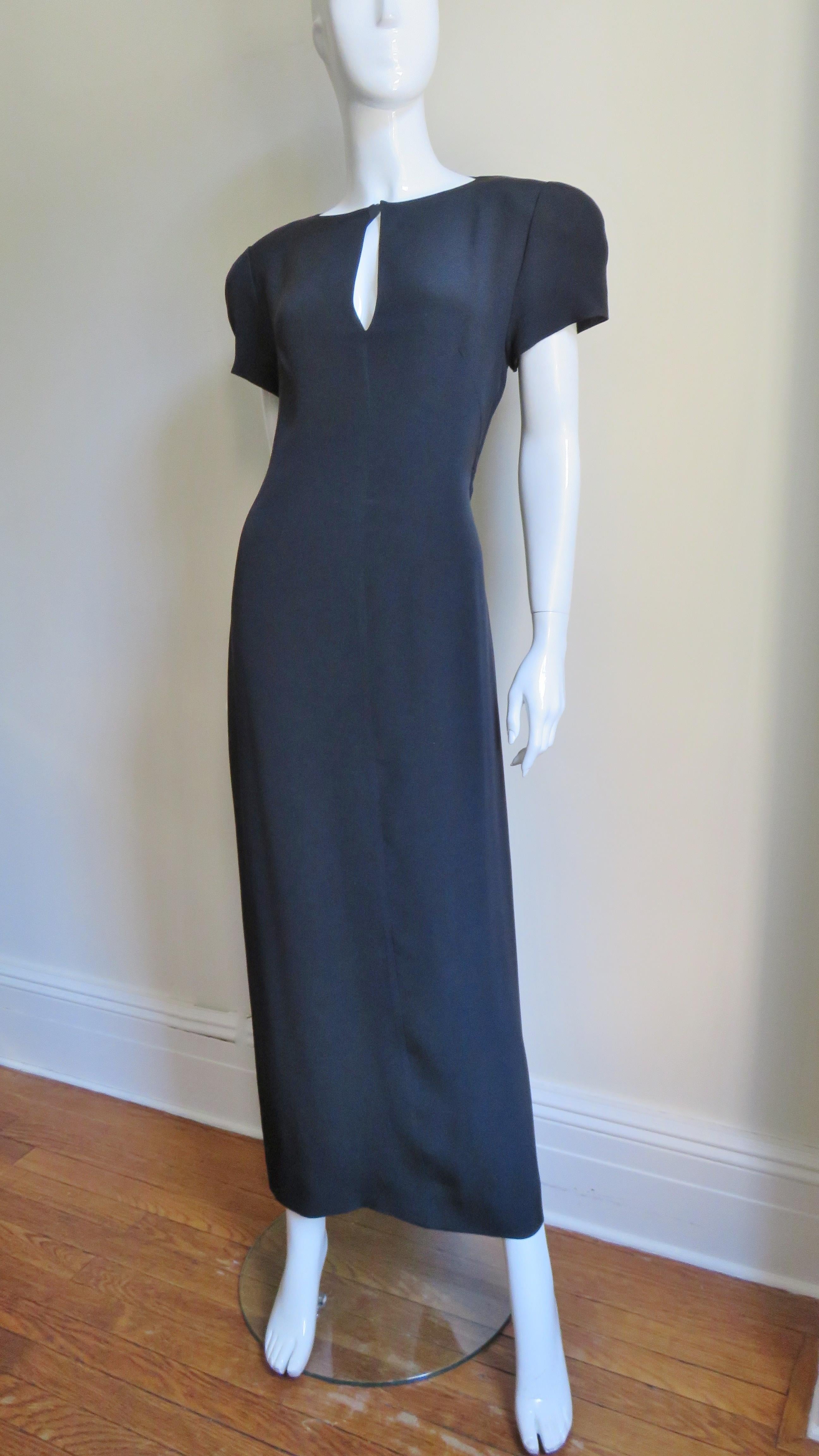 A great black silk dress from Krizia.  It has short sleeves and a front keyhole closing at the crew neck with a hidden button above it.  It skims the body then falls straight to the hem.  There is a dramatic slash diagonally across the upper back
