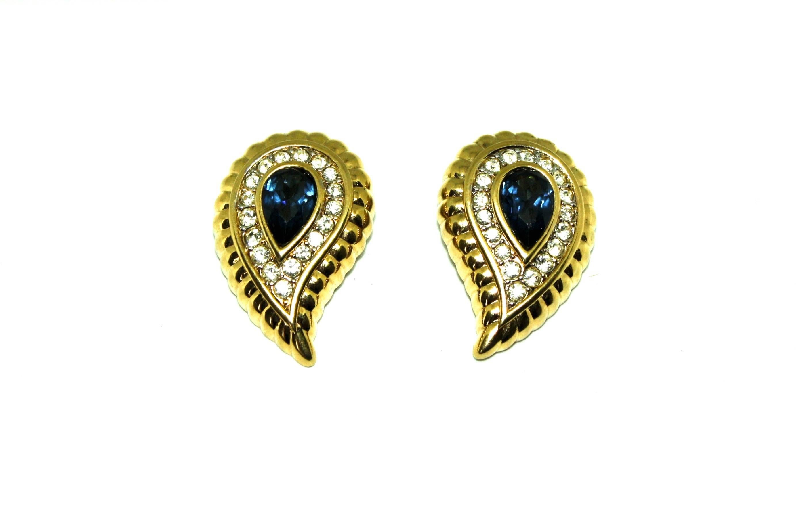 Paisley shape clip earrings featuring a large sapphire coloured glass stone and smaller white rhinestones by Nina Ricci. The name Nina Ricci its marked on the reverse of both clips along with a copyright mark. These earrings have been dated to the