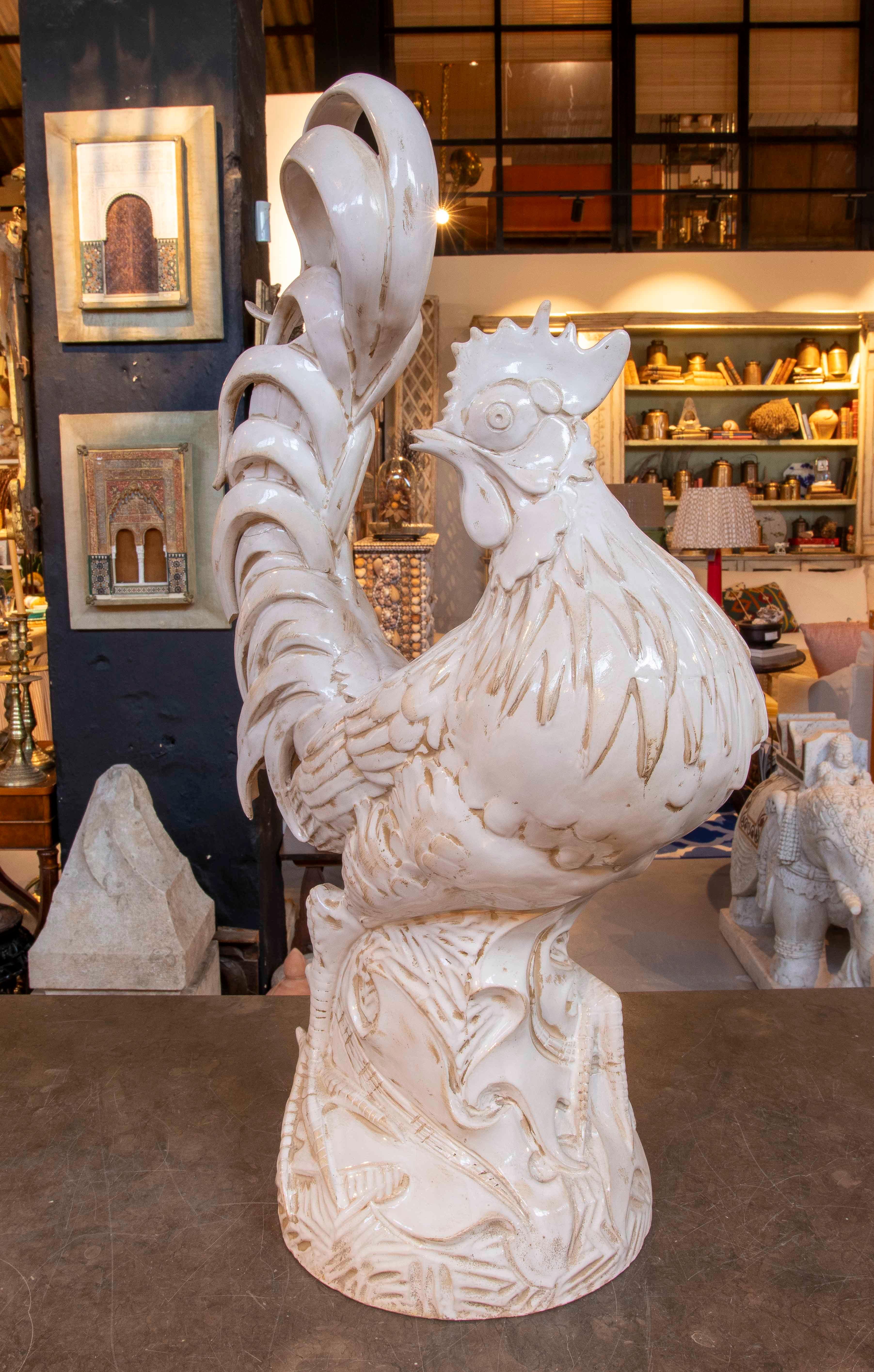 Spectaculaire sculpture de coq en céramique émaillée blanche, au design très dynamique et détaillé. La pièce se distingue par sa crête et ses plumes en relief, notamment sur la queue, qui s'incurve élégamment, créant une silhouette très