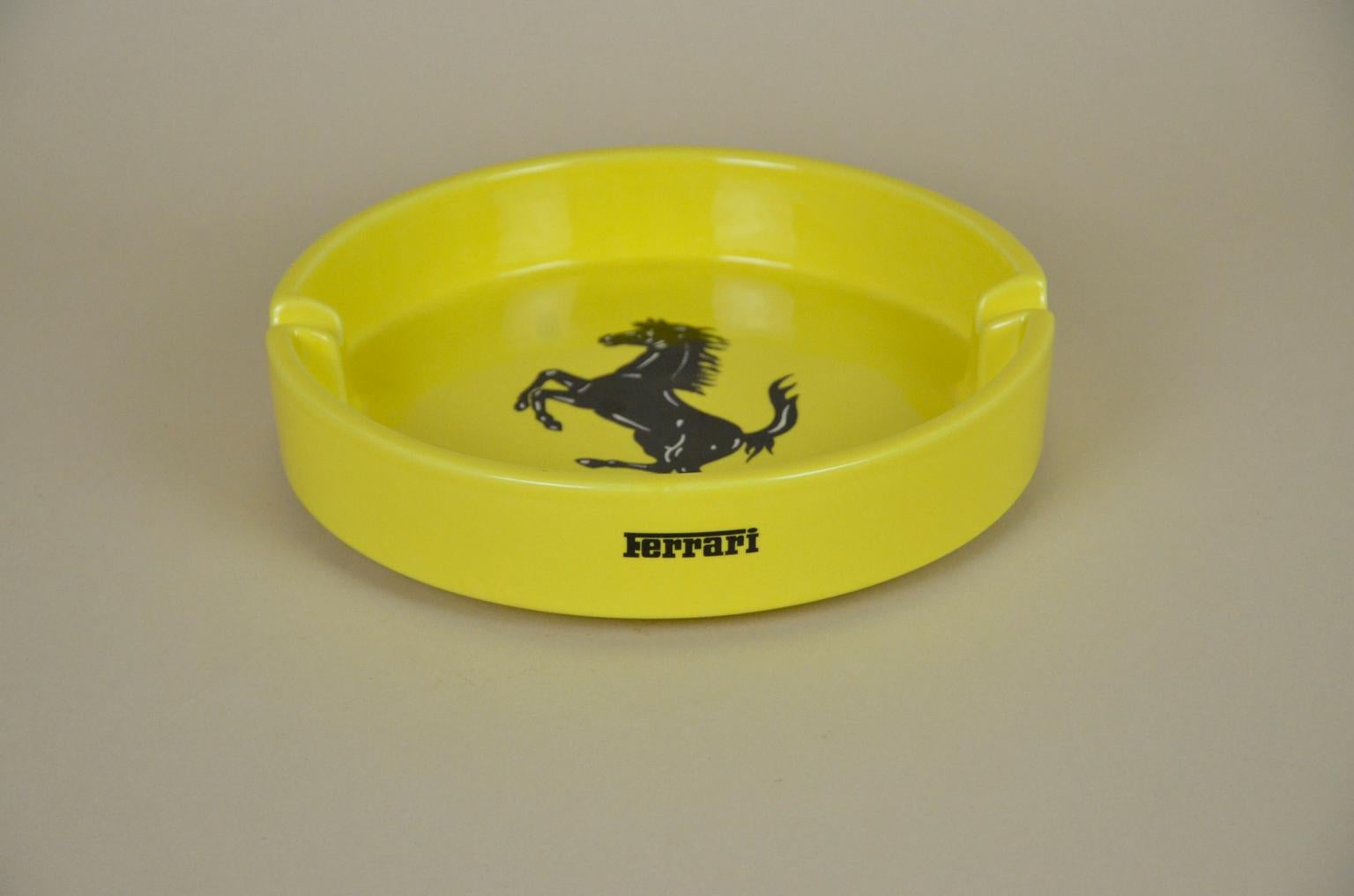 Ferrari advertising ashtray in yellow ceramic made in Italy by Bitossi in the 1980s. This large circular ashtray has a black Ferrari horse symbol in the center and one Ferrari logo outside on the border. It's also marked Bitossi on bottom.