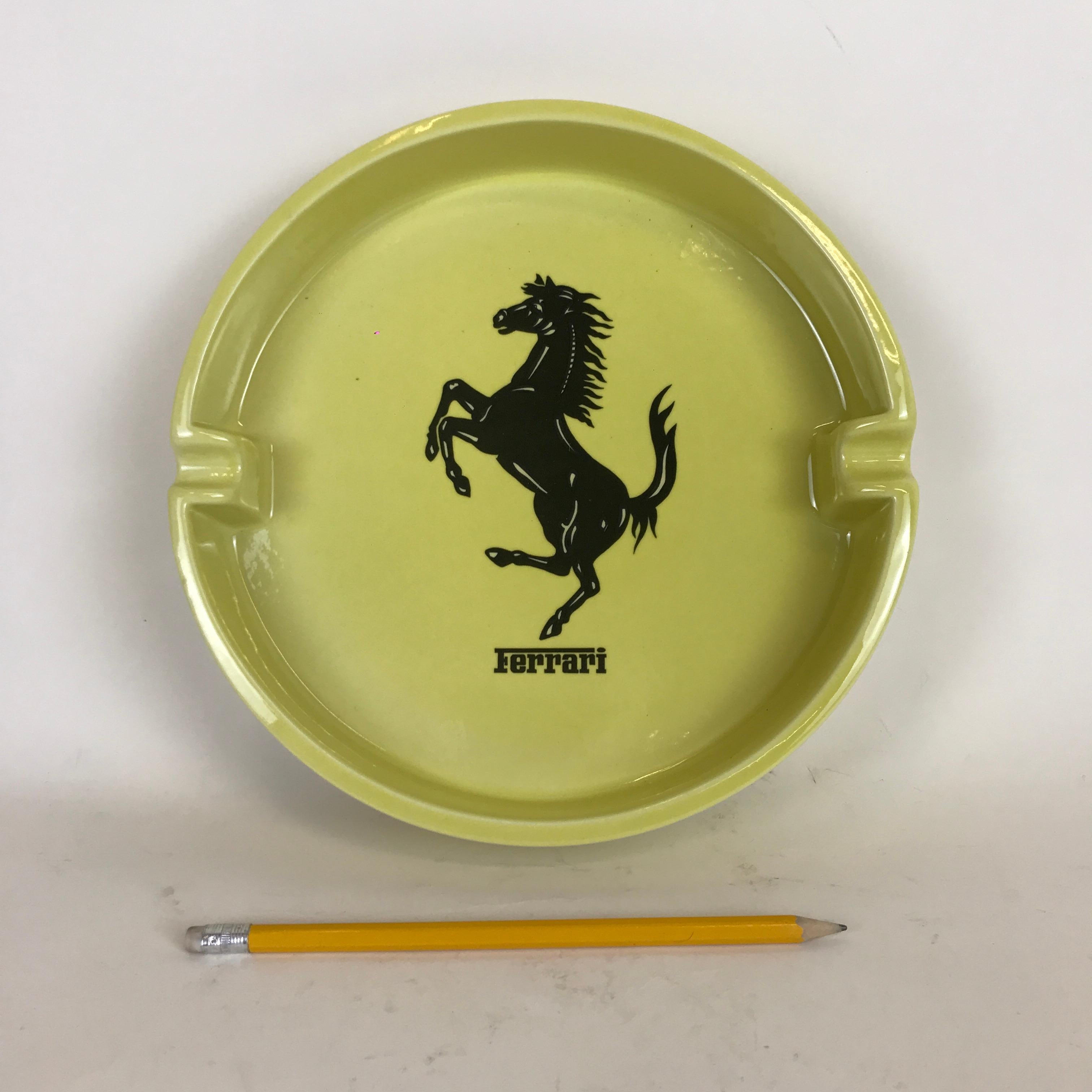 Ferrari advertising ashtray in yellow ceramic made in Italy by Bitossi in the 1980s. This large circular ashtray has a black Ferrari horse symbol in the centre and one Ferrari logo outside on the border. It's also marked Bitossi on bottom. 

The