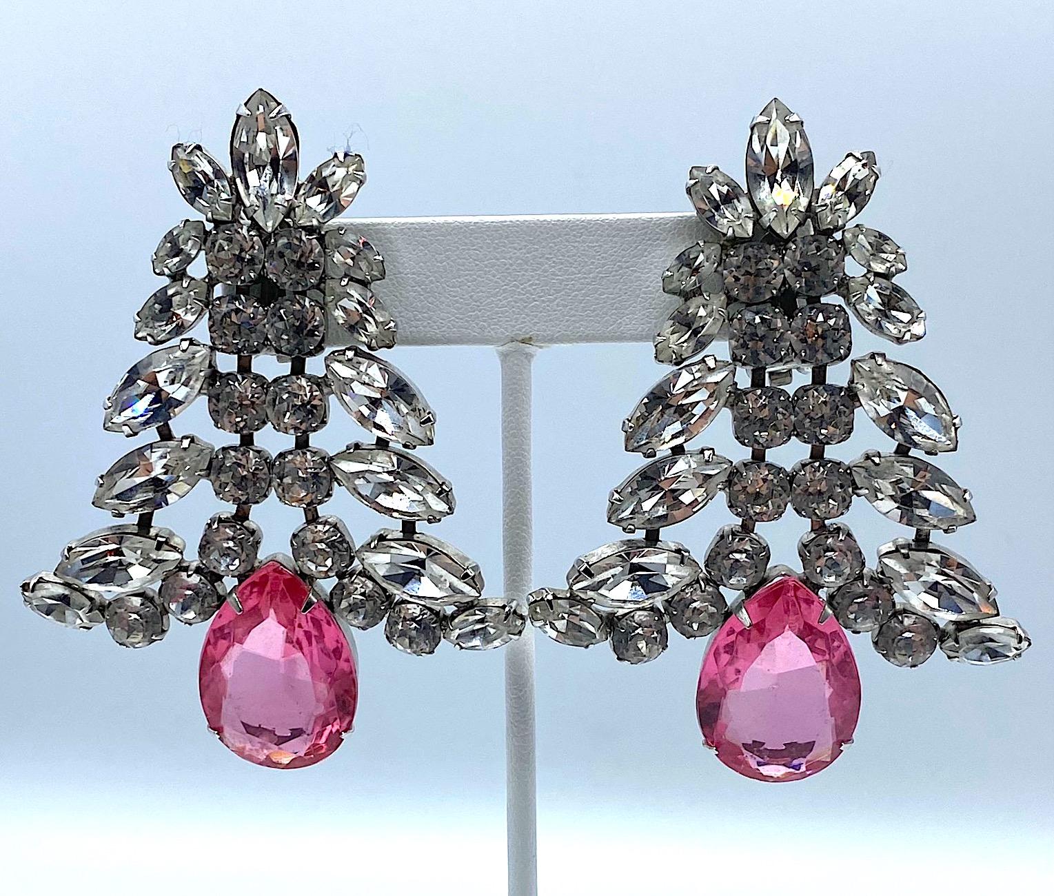 A fabulous pair of large rhodium plated and rhinestone set earrings with pink crystal stone. The earrings are set with round rhinestones along the center with various size marquise shape rhinestones along the top sides forming a bell shape. The