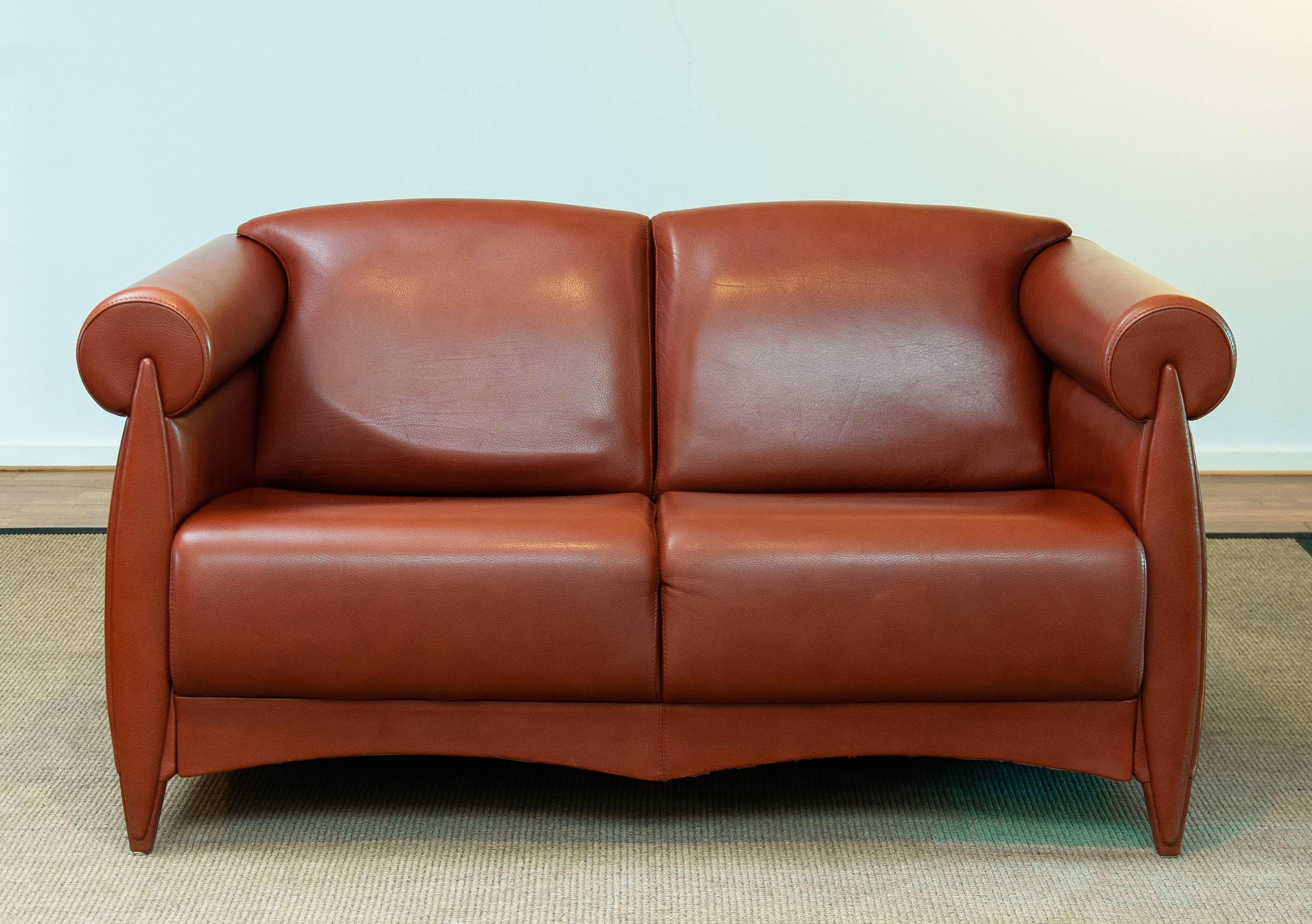 Questo elegante divano a due posti, realizzato da Klaus Wettergren e prodotto da Q Production, presenta un design sofisticato e contemporaneo. Rivestito in pelle color cognac, il divano emana calore e lusso. La sua silhouette distintiva è