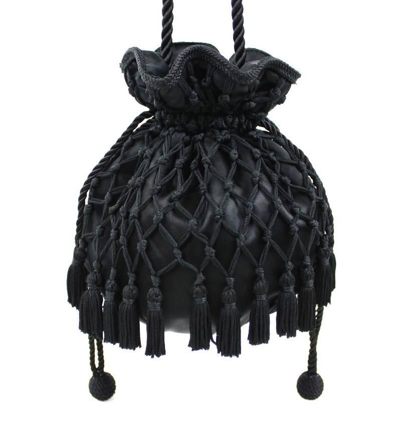 The most elegant little tassel bag from 1980s Lord & Taylor! Black satin drawstring pouch wrapped in braided netting, with tassel trim all along the bottom. Bag pulls closed with two drawstrings, each with a cord ball at the end. Long, twisted cord