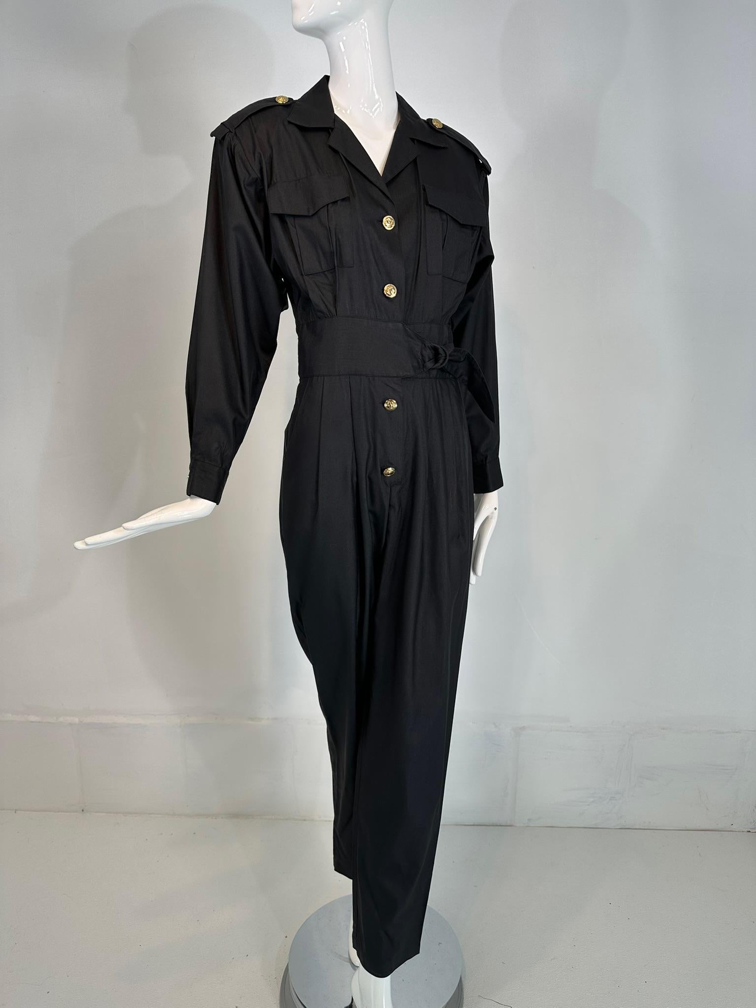 1980 Lord & Taylor - Combinaison de tailleur en soie noire matte avec boutons dorés, taille 6.
Combinaison à revers cranté se fermant sur le devant par des boutons dorés du buste jusqu'en dessous de la taille (braguette), deux poches poitrine à