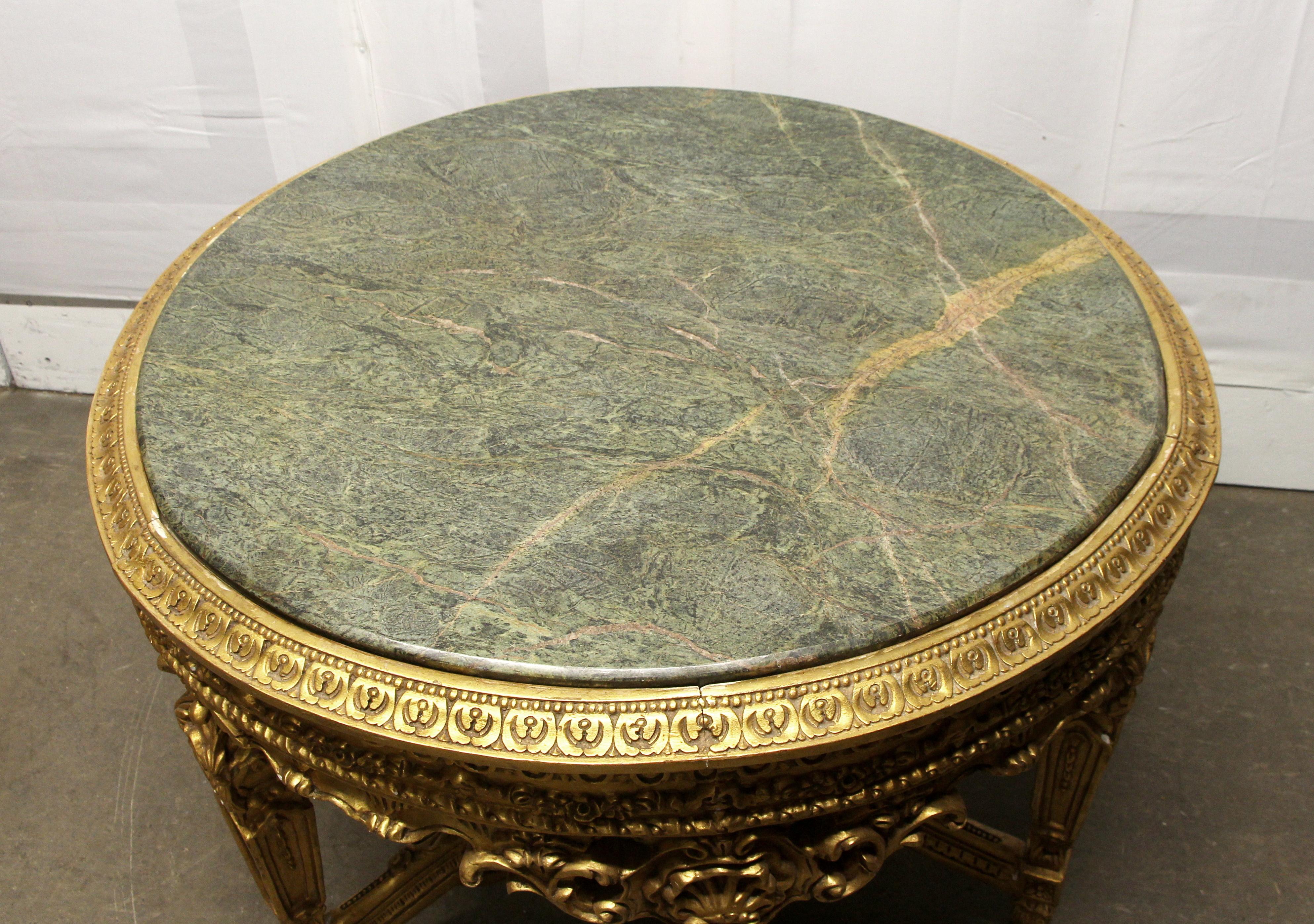 1980s French round table done in the style of Louis XVI. With a veined green round marble top and a highly ornate carved gilt wood frame. Minor wear due to age and use. This can be seen at our 302 Bowery location in NoHo in Manhattan.