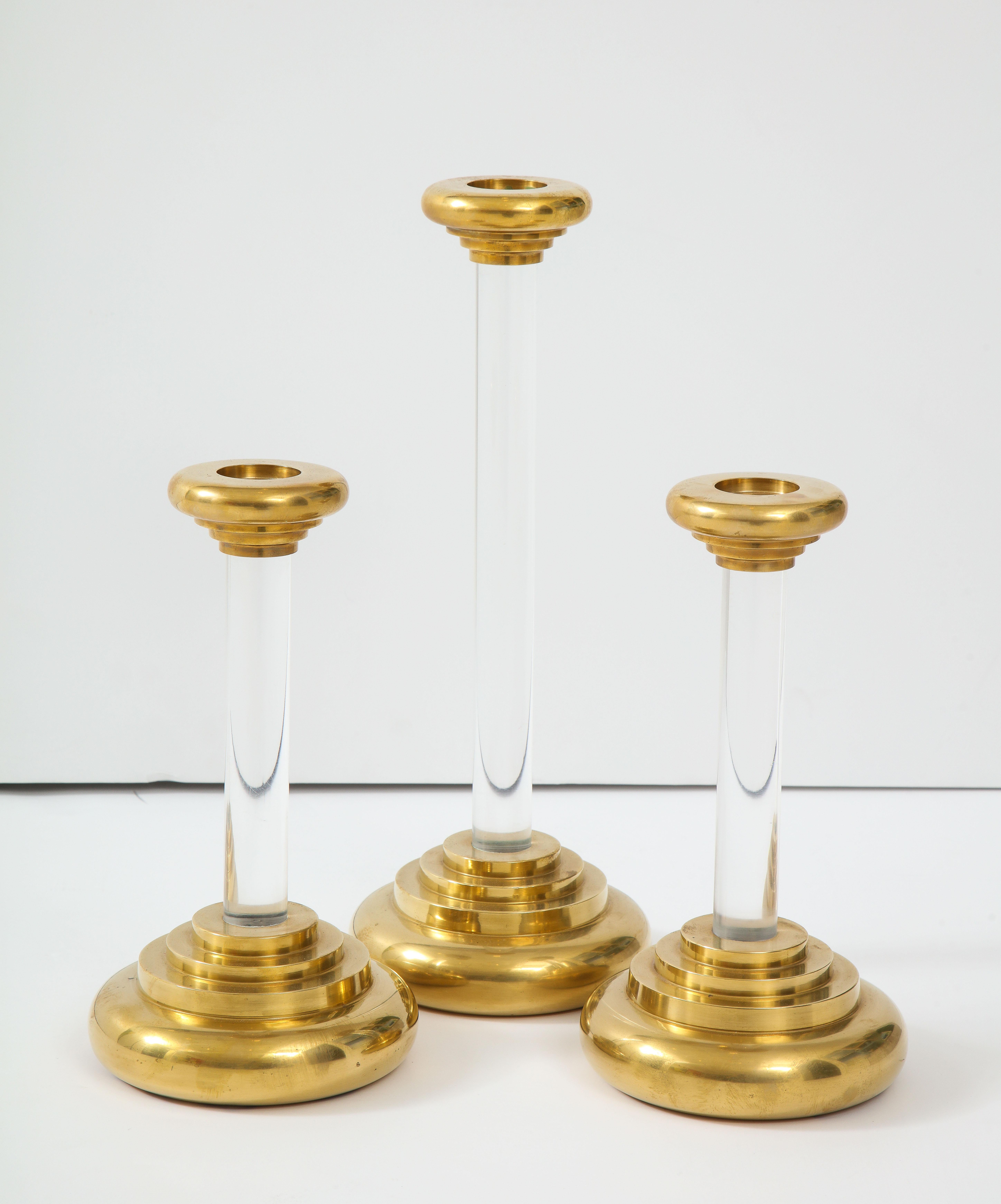 Large set of three 1980s modern Lucite and brass candleholders.

The two smaller candleholders height is 12