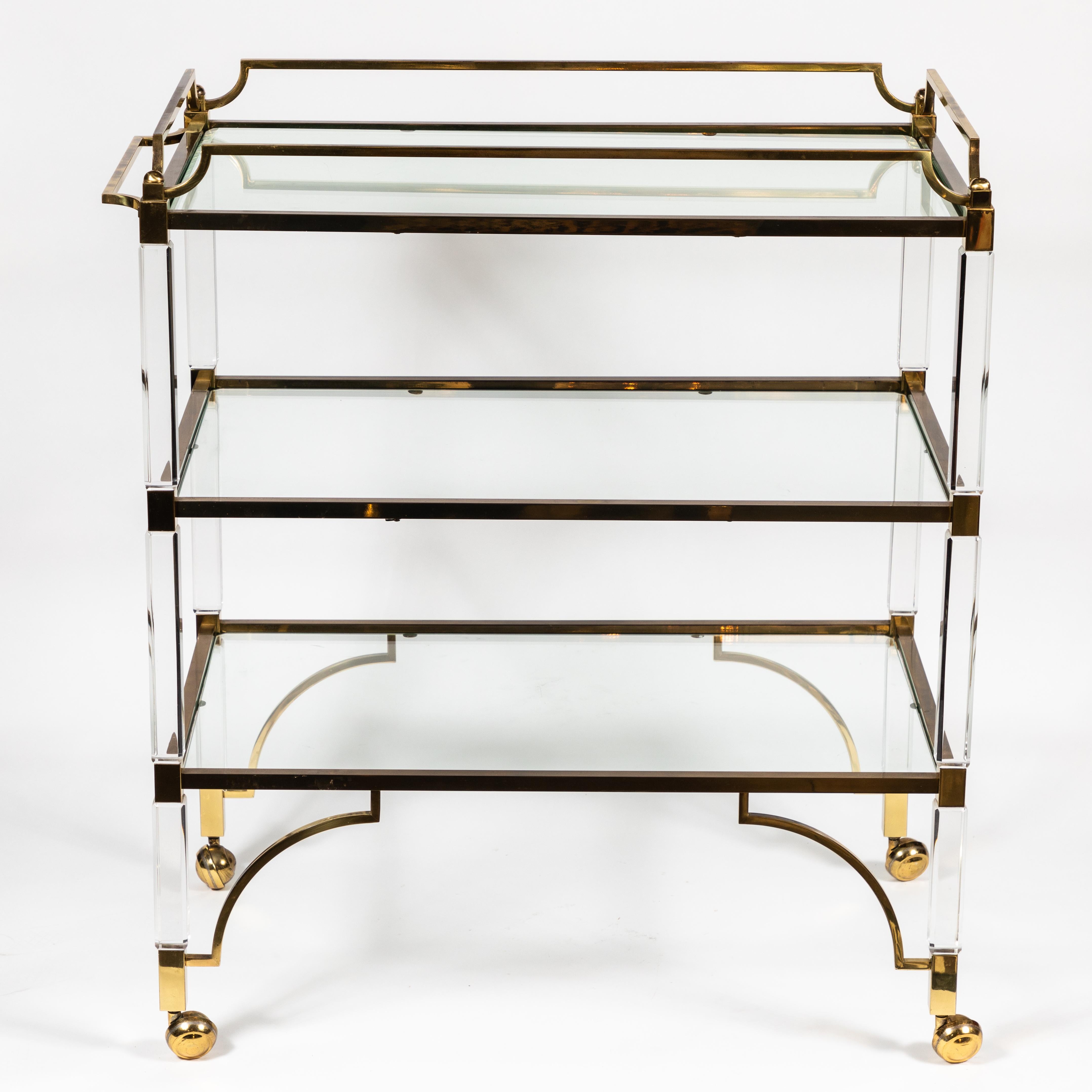 Chic, yet functional bar cart in Lucite with brass frame and detail. Glass shelves. Excellent vintage condition.
