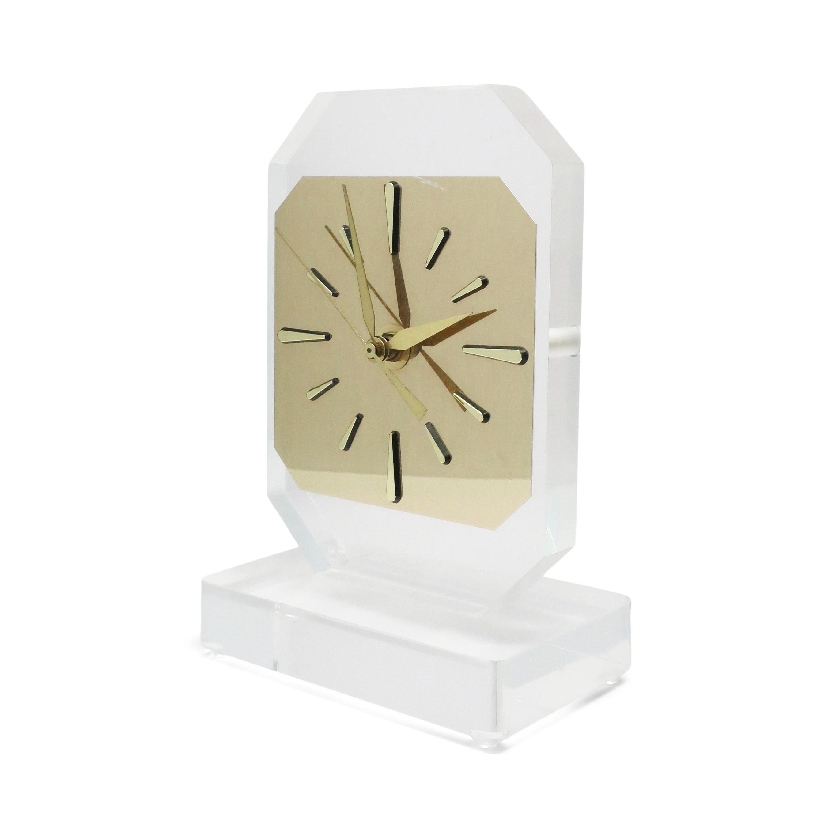 With a rectangular base, tall body, and brass colored face and hands, this sleek lucite desk, table or mantle clock has clean lines, simple elegance, and a perfect modern sophistication.

In excellent condition and works perfectly.

Measures: