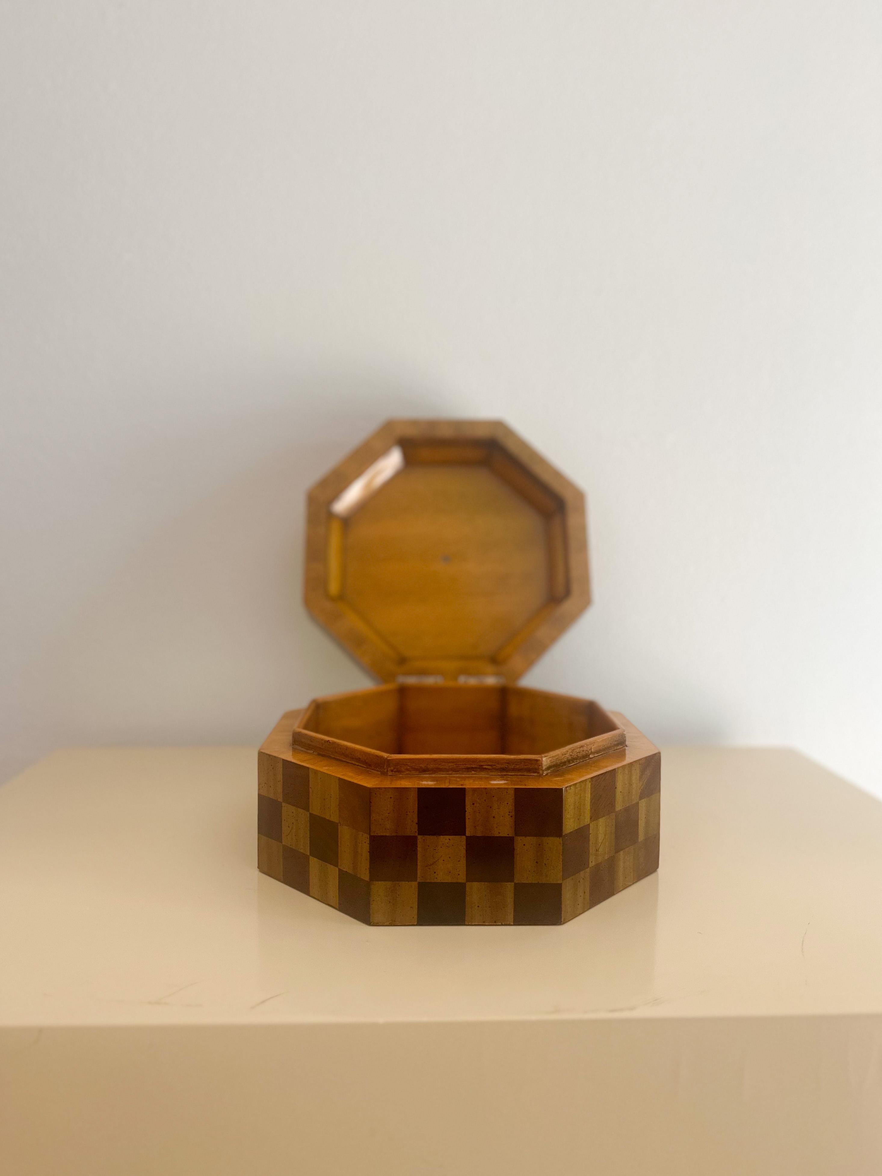 Beautiful octagonal mahogany box with checkered parquetry, hinged top, silver finial, and fully-finished wood interior lining, hand-made in the Philippines by Maitland Smith, c.1980s. This handcrafted piece is a work of art, showing utmost attention