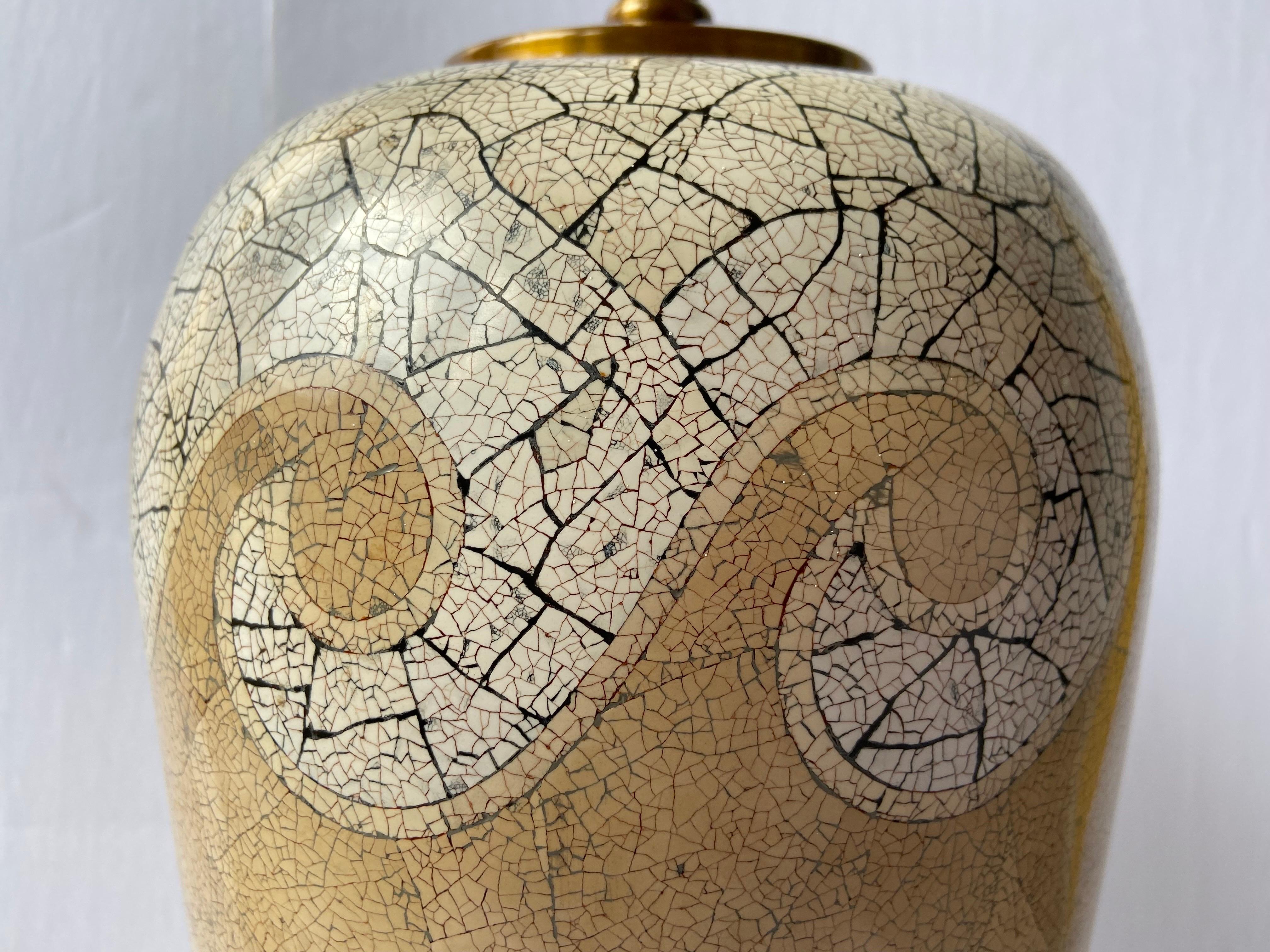 A vintage table lamp by Maitland Smith with an all over appearance of eggshell craquelure in the spirit of Jean Dunand. This lamp features a bold wave design in white and black at the shoulders and foot of the form with a tan design in the center.