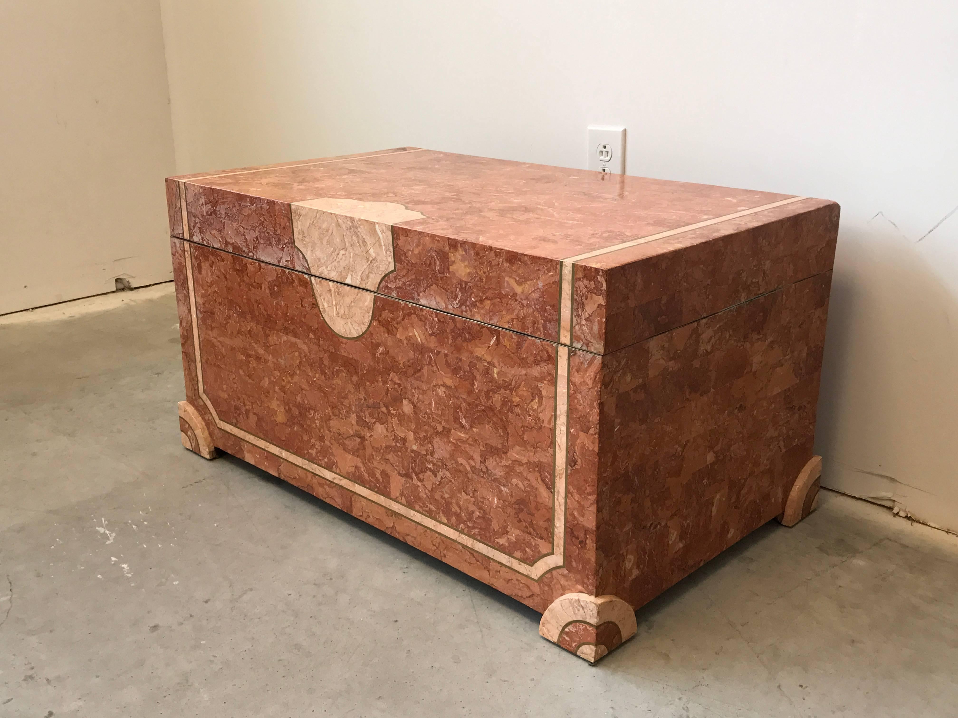 Offered is an exquisite, Robert Marcius for Casa Bique trunk, circa 1980s. Covered in tessellated marble stone of contrasting coral shades, with squared feet that have a contrasting rounded inner edge, adding sculptural detail to the piece. Brass