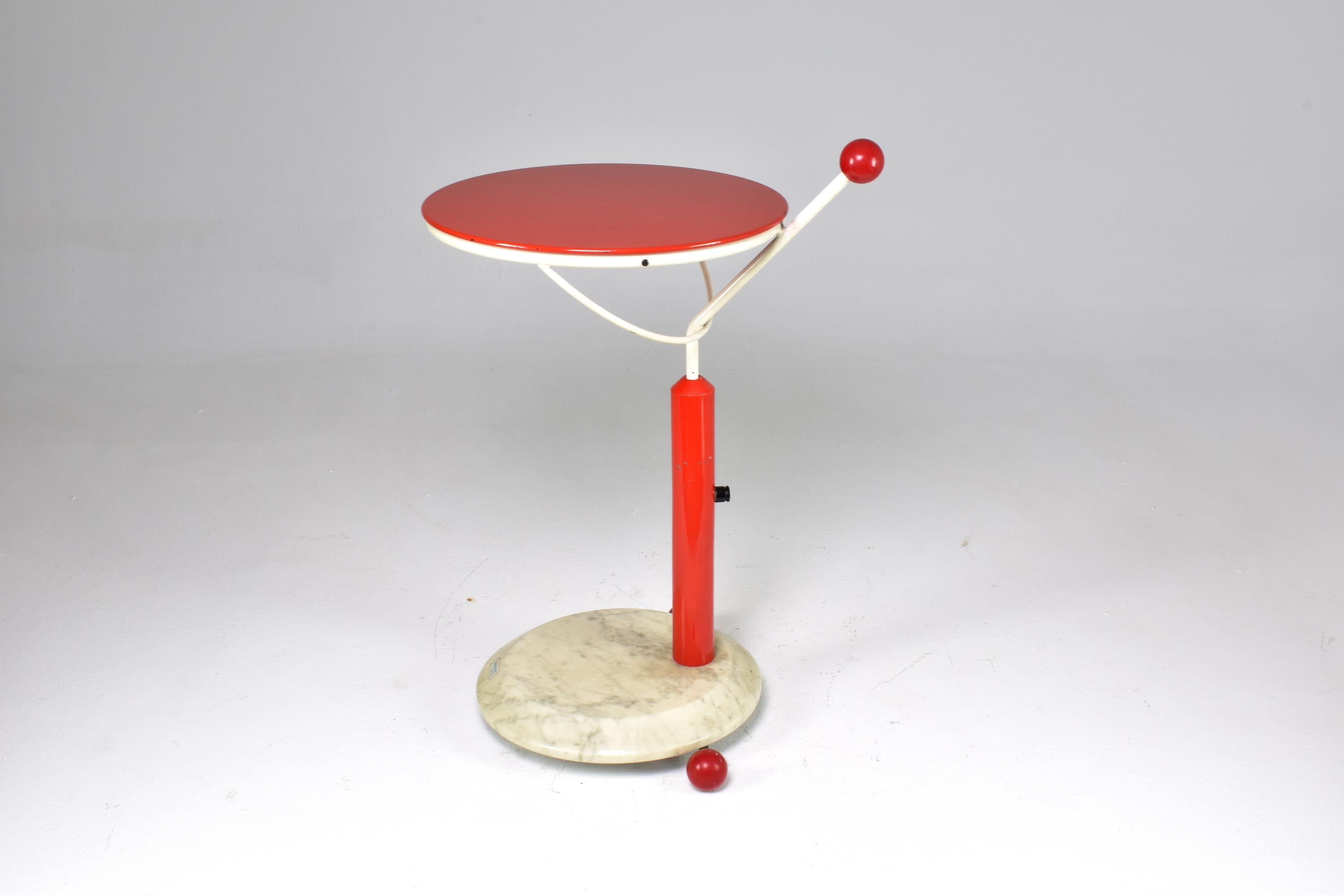 A fantastic 1980's rolling cart composed of a white carrare marble base, red synthetic wheels and stem, a white metal frame, and a red swiveling tray. The cart is designed for maneuverability, with a conveniently placed handle boasting a plastic
