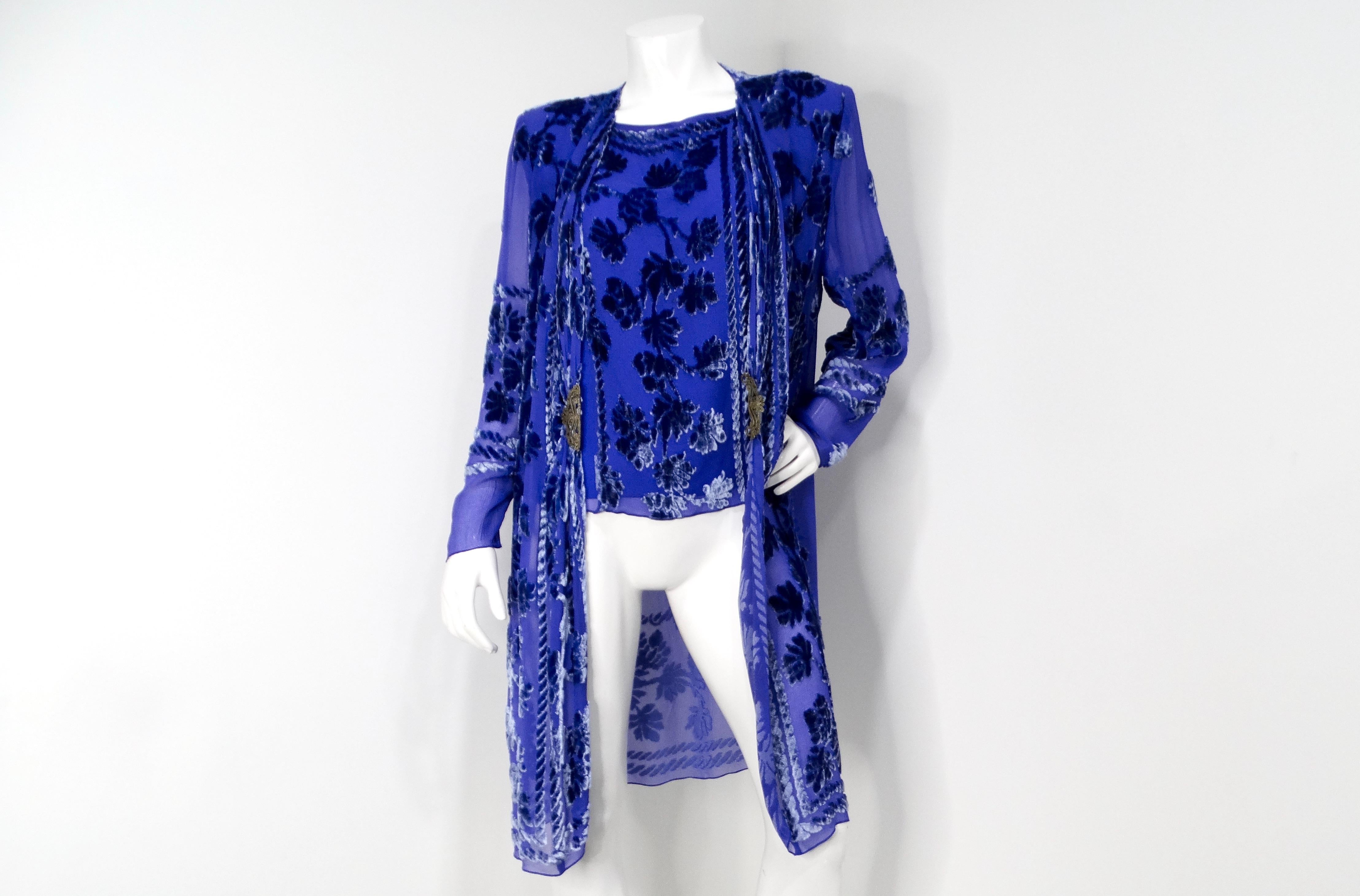 The 1980s Marian Clayden Electric Blue Burnt-Out Velvet Kimono is a striking piece that captures the essence of bold vintage fashion. This exquisite kimono-style jacket features a vibrant blue hue, adorned with a sophisticated velvet floral print