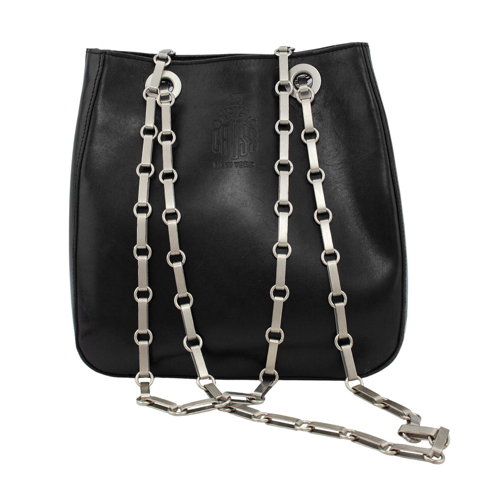Mark Cross 1990’s black leather small bucket bag with silver flat link double chain handles. Can be worn with the chains doubled on one shoulder or single cross body. Black semi polished leather with blind stamped Mark Cross logo on the exterior.