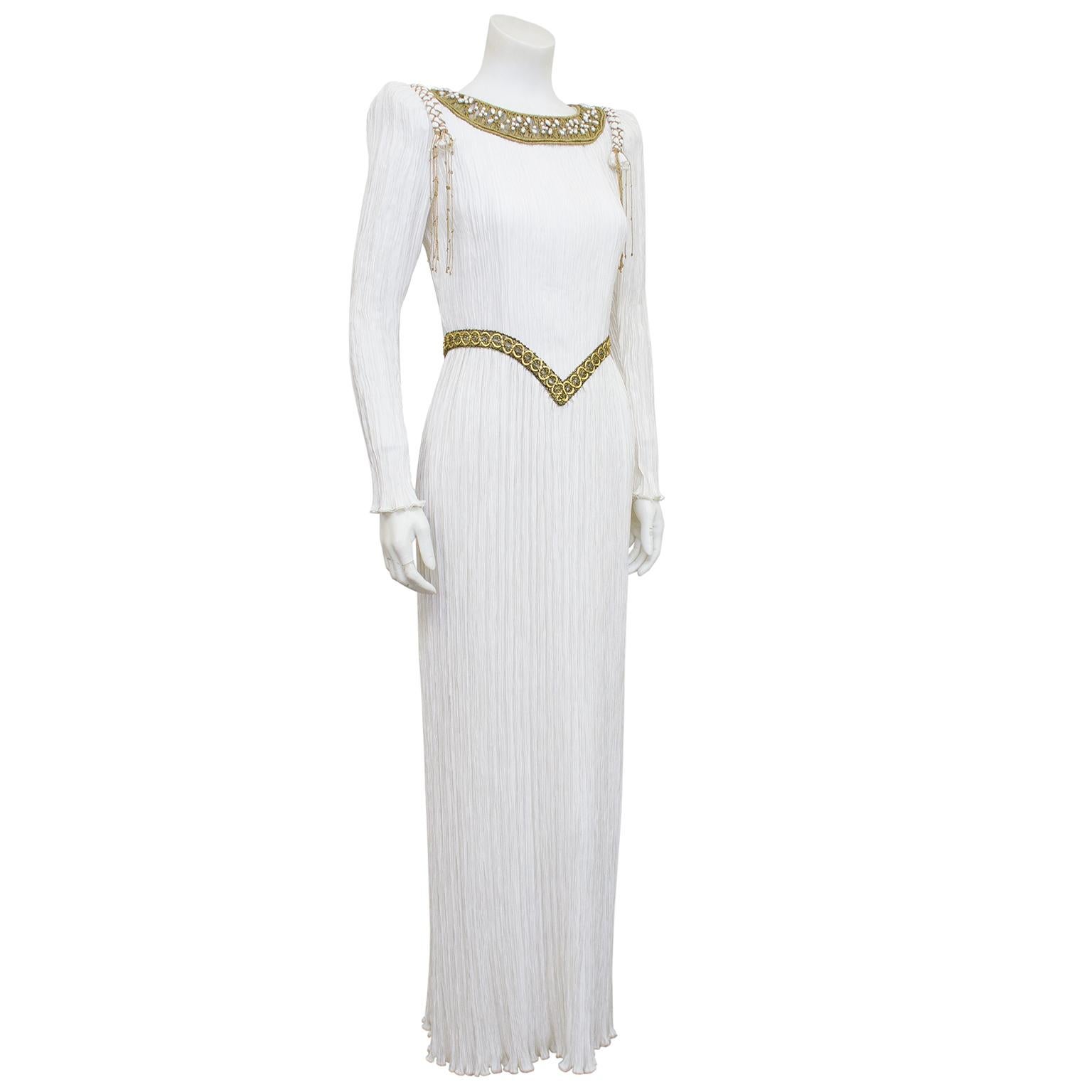 1980s fabulous white micro pleated Mary McFadden gown. Long sleeves with fitted bodice and straight skirt. Beautiful metallic gold macramé and pearl neckline, gold wrapped rope detail at shoulders and gold v shaped detail at waist. Would be a