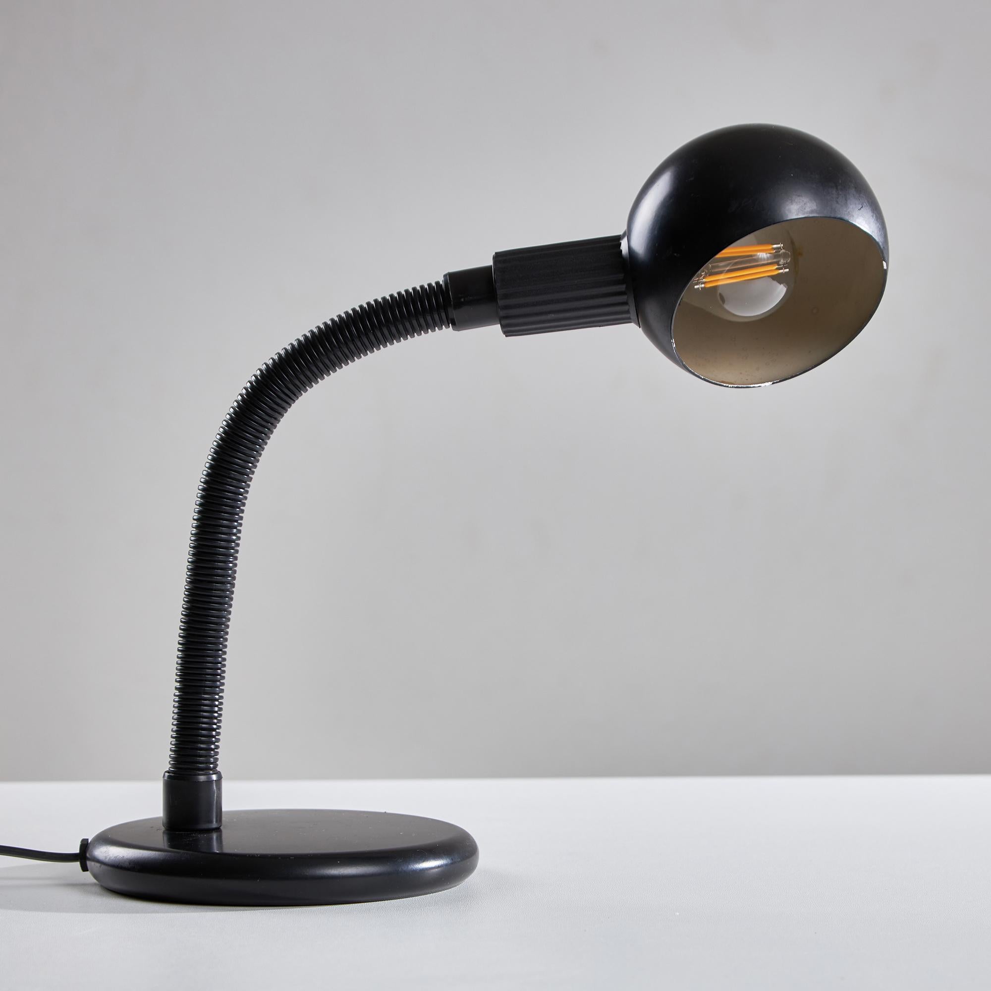 This 1980s matt black desk lamp features an adjustable stem, allowing you to direct light precisely where you need it. The spherical shade casts a warm glow, enhancing any workspace or reading nook. With a sturdy round base, it stands firmly in