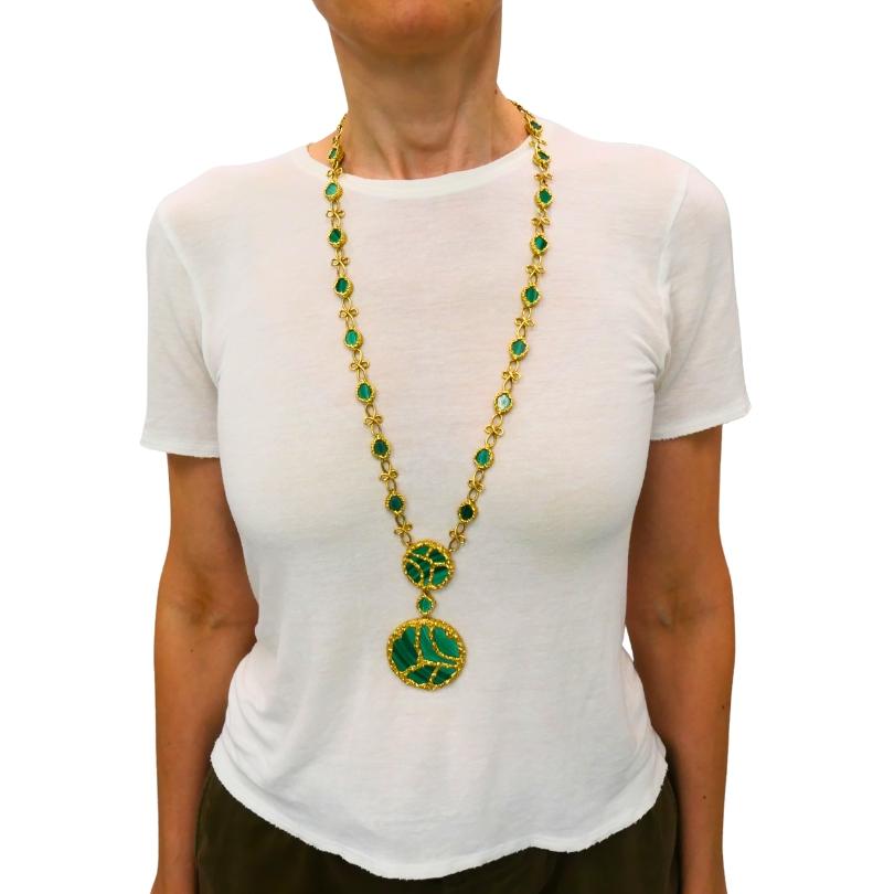 Collier à pendentifs en or 18 carats et malachite de Mauboussin, vers les années 1980.
Conçu en or jaune riche, le collier présente deux grands pendentifs circulaires sertis de panneaux de malachite incrustés. Le vert intense de la malachite, avec