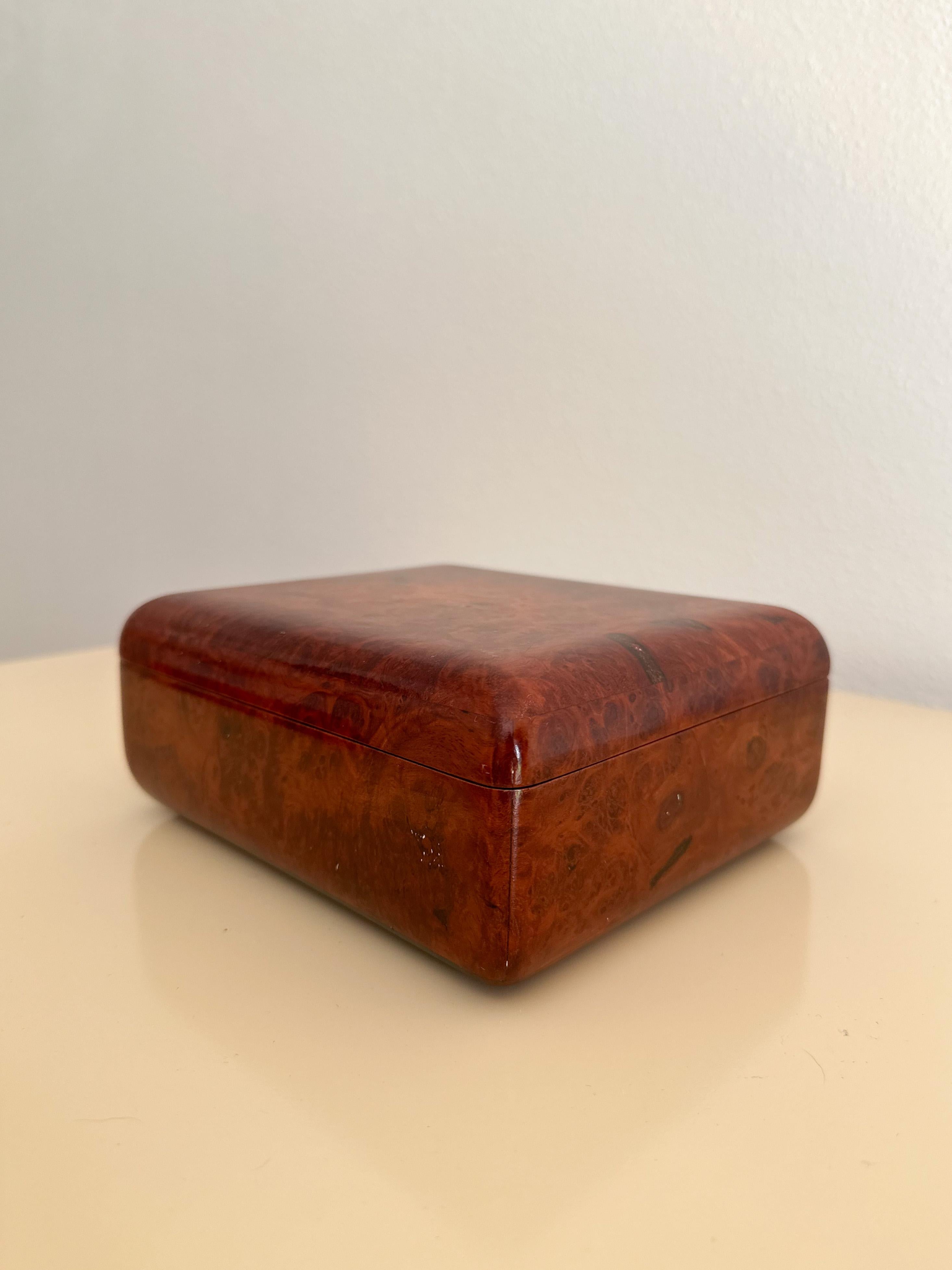 Beautiful lacquered burlwood box with rounded edges and hinged top, perfect for storing jewelry, cigars, etc. Medium-dark brown with red tones and beautiful grain. In great vintage condition with minor pitting.