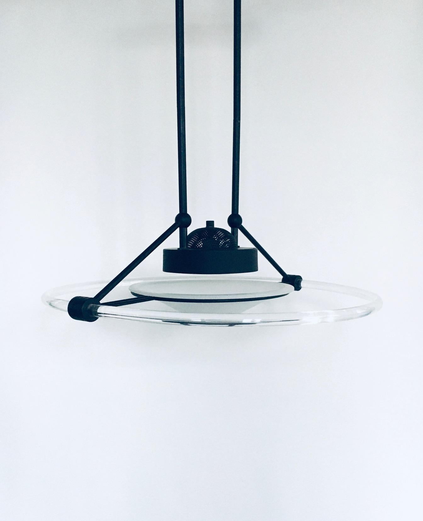Lampada a sospensione vintage in stile Memphis, realizzata in Italia negli anni '80. Metallo nero con anello in perspex e vetro opalino bianco in questa lampada a sospensione dal design moderno. Lampada alogena funzionante. La lampada è in ottime