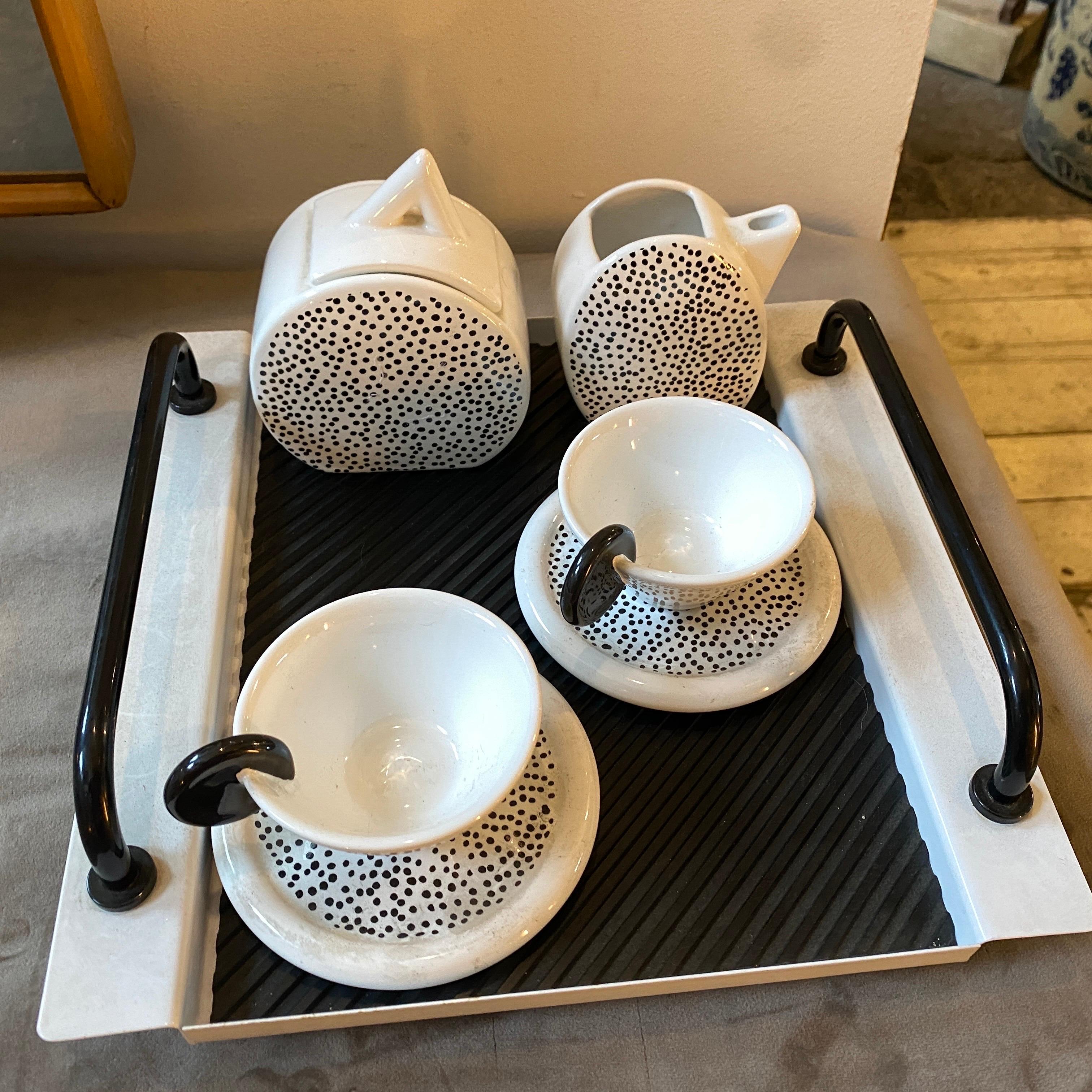 A Memphis Milano  tea set designed and manufactured in Italy in the Eighties by MAS, it's composed by a black and white metal tray, a black and wwhite ceramic sugar bowl height 13 cm, a creamer heeight 10 cm, two coffee cup. All the 5 pieces are in