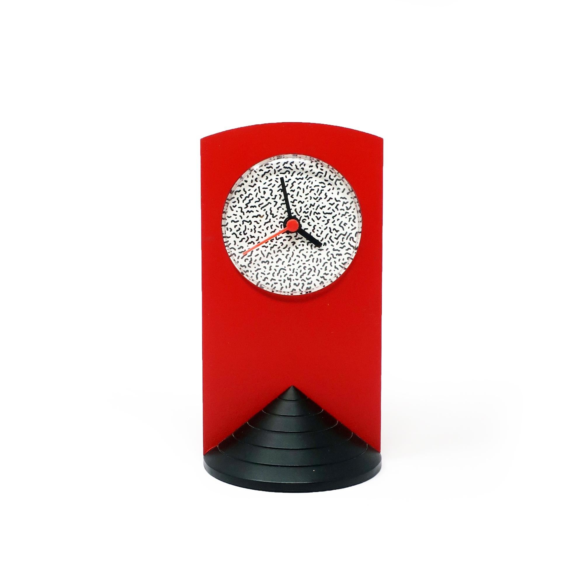 A perfectly designed 1980s Memphis Milano-inspired desk clock with a black triangular base, red plastic case, and black and white squiggle face.  Looks like it could've been designed by Ettore Sottsass or George Sowden and Nathalie du Pasquier for