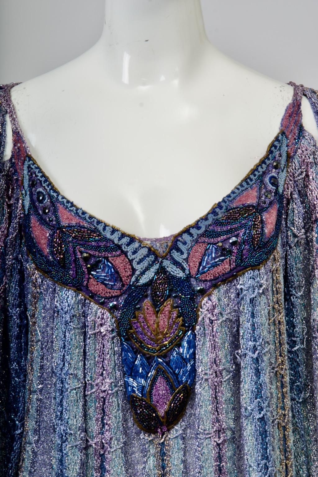 Unique en son genre, cette tunique est composée de rangées verticales de fils métalliques ajourés dans des tons bleus et lavande. Elle présente des manches papillon et des encolures échancrées à l'avant et à l'arrière. Sur le devant, l'encolure est