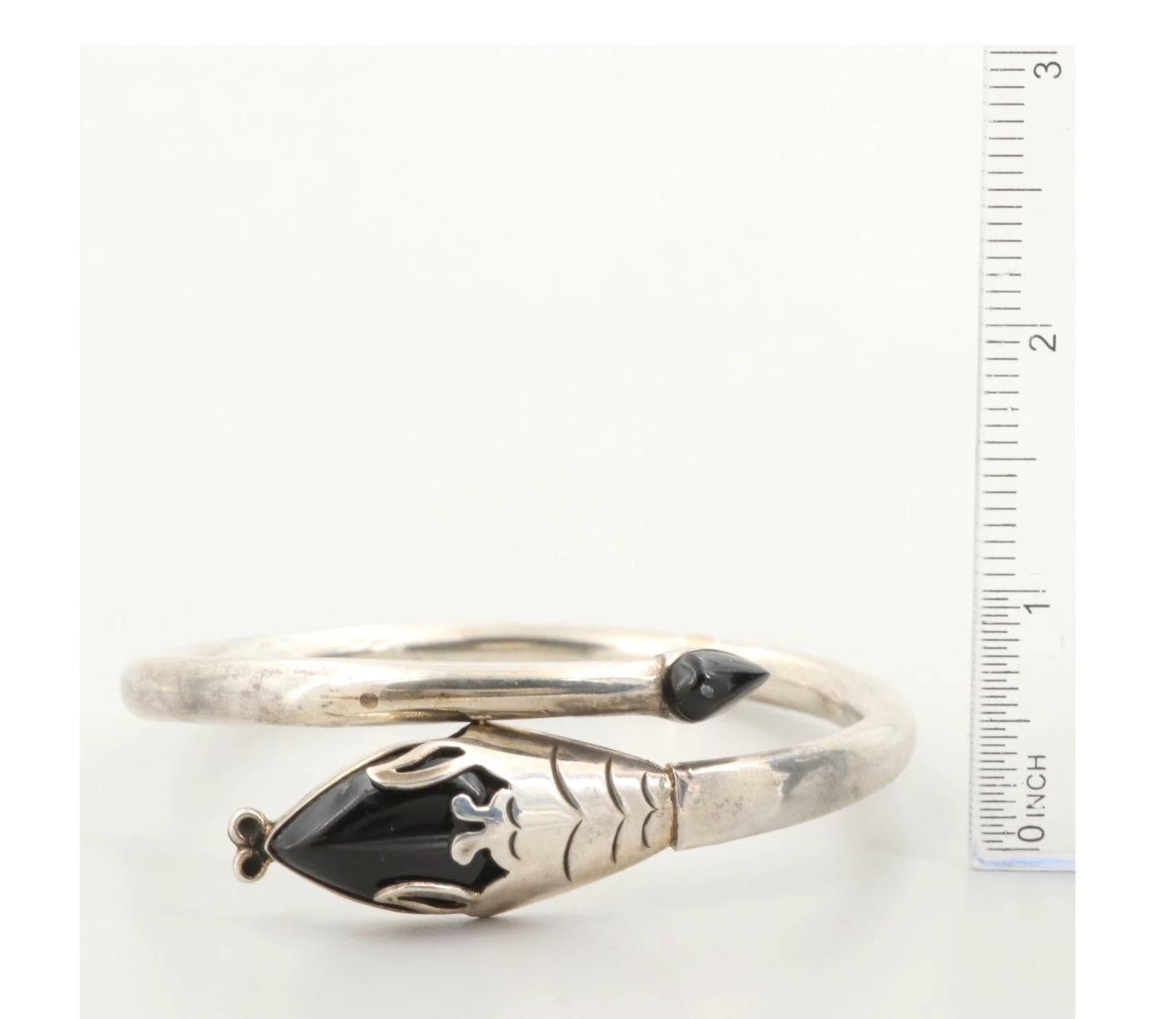 Exceptional 1980's Mexican Modern Sterling Silver and Obsidian Snake Bangle Bracelet is by the highly collectible Taxco silversmith known as Two Trees. 

Brilliantly handwrought, here the ancient image of Aztec deity Quetzalcoatl—the mythic 