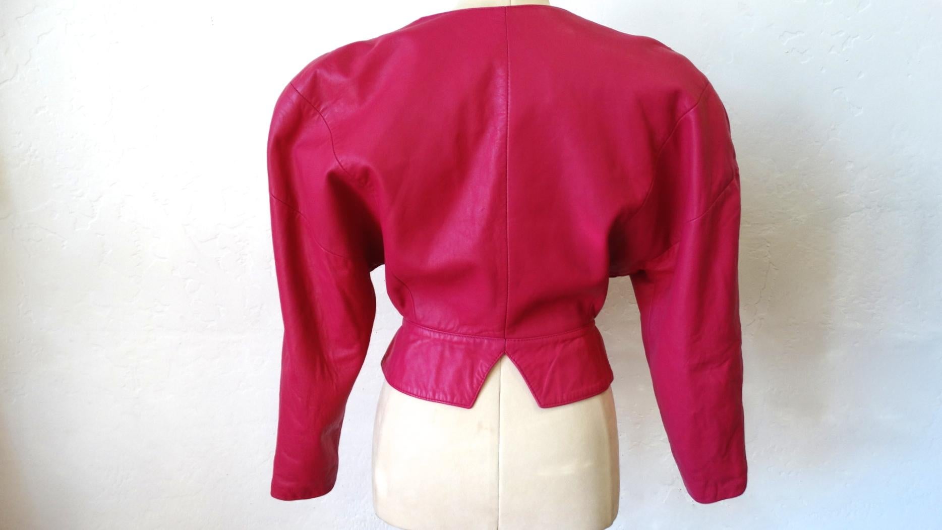 Embrace Your Inner 80s Glam Girl With This Michael Hoban Pink Cropped Leather Jacket! Features dolman sleeves, snap front buttons, strong shoulders and asymmetrical lapels. The lapel on the right includes a piece of tonal velcro, allowing the wearer