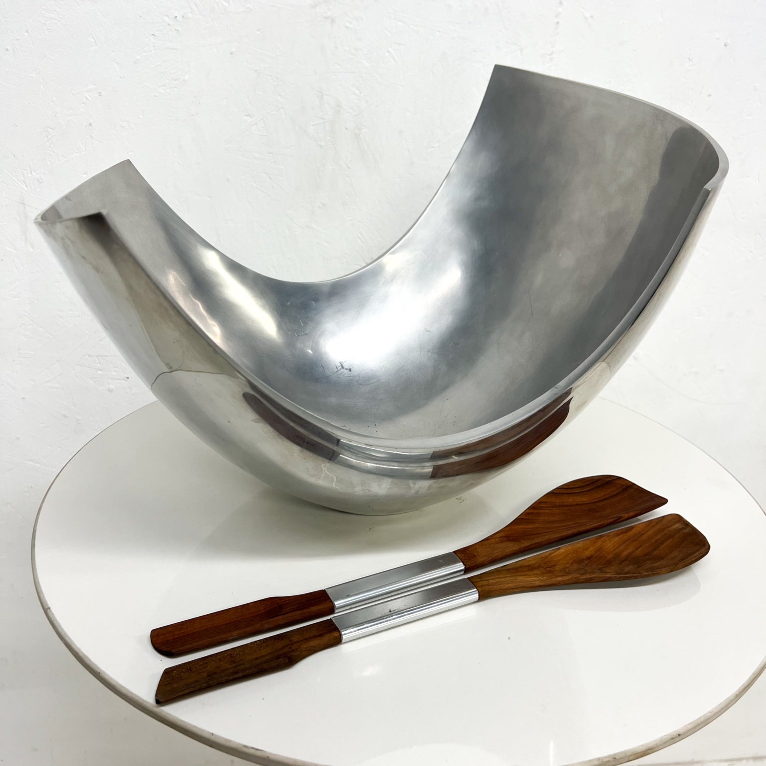 Stunning Polished Aluminum serving bowl by Michael Lax for METAAL
13 tall x 18.5 w x 13.5 d    Salad servers 16 long
Set includes sculptural salad servers in wood and aluminum (different maker).
Preowned unrestored vintage condition
See images