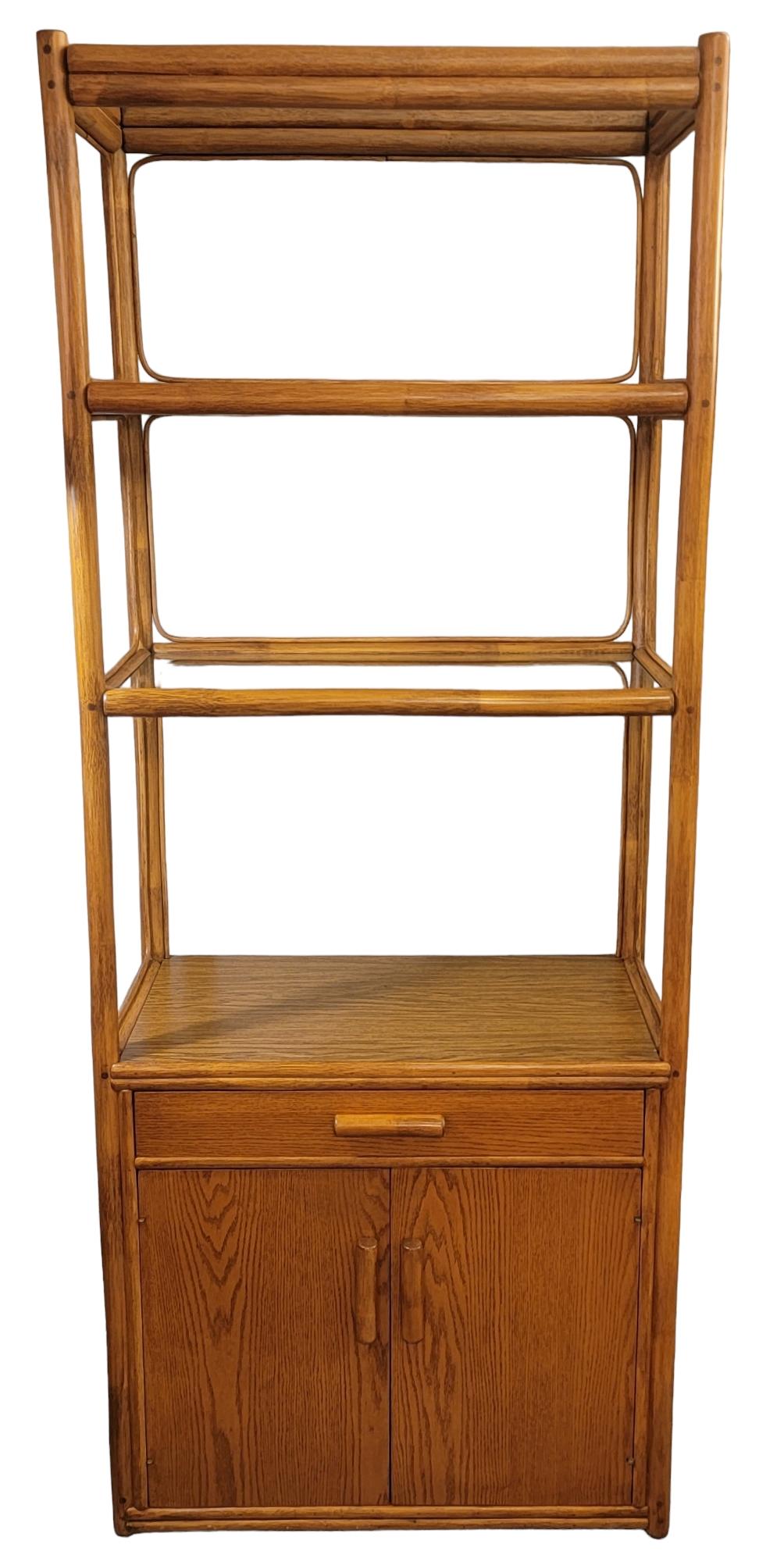 Three Tier Bamboo Shelf with two door storage compartment that has a shelf within. This bamboo shelf is a strong yet light weight etagere, there are 2 glass shelves and one of the glass shelves has a very minor crack to it. It does not hinder the