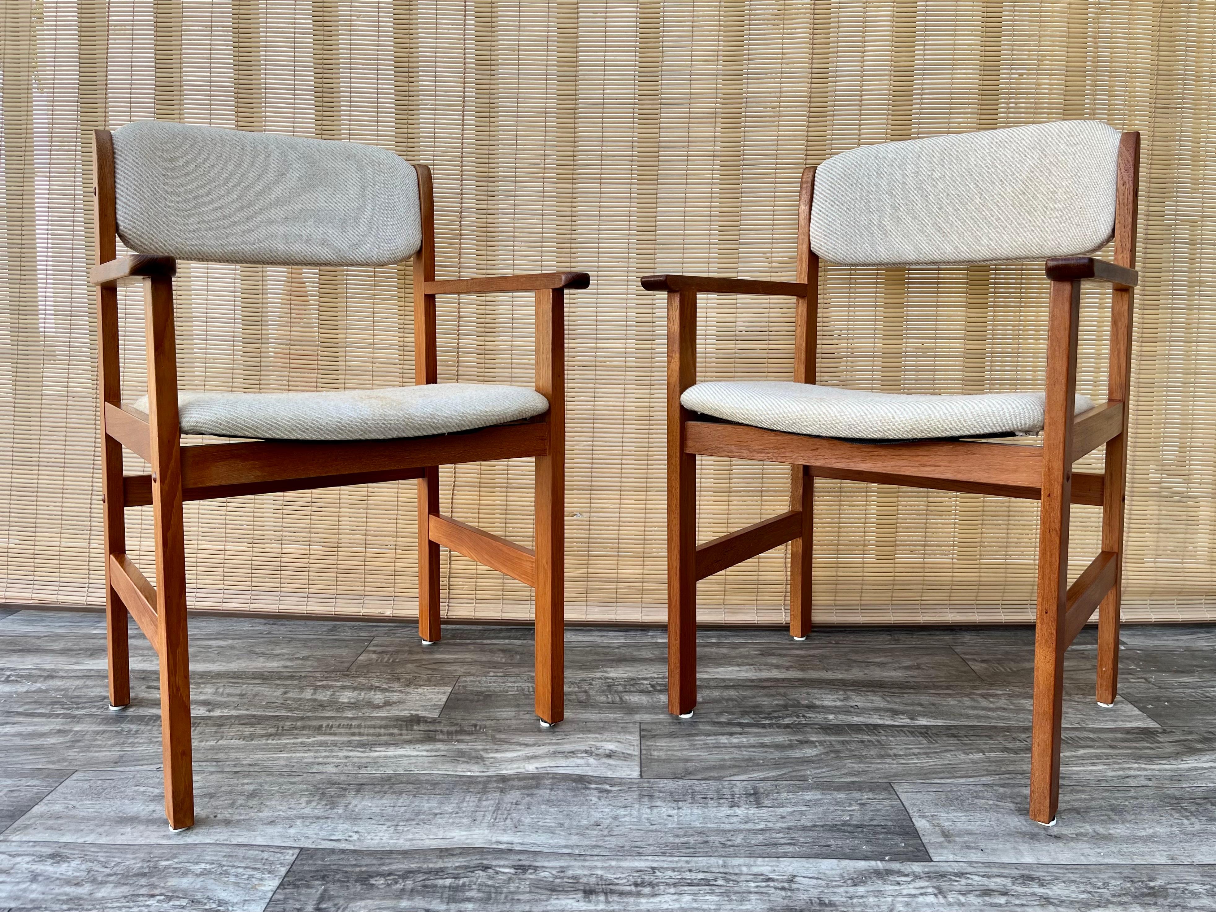 A pair of 1980s Mid-Century Danish Modern Style Captain Chairs by Benny Linden Design. 
Feature a solid teak frame in a minimalist Scandinavian Modern Design, and upholstered seats and back rests with the original cream color fabric. 
The teak
