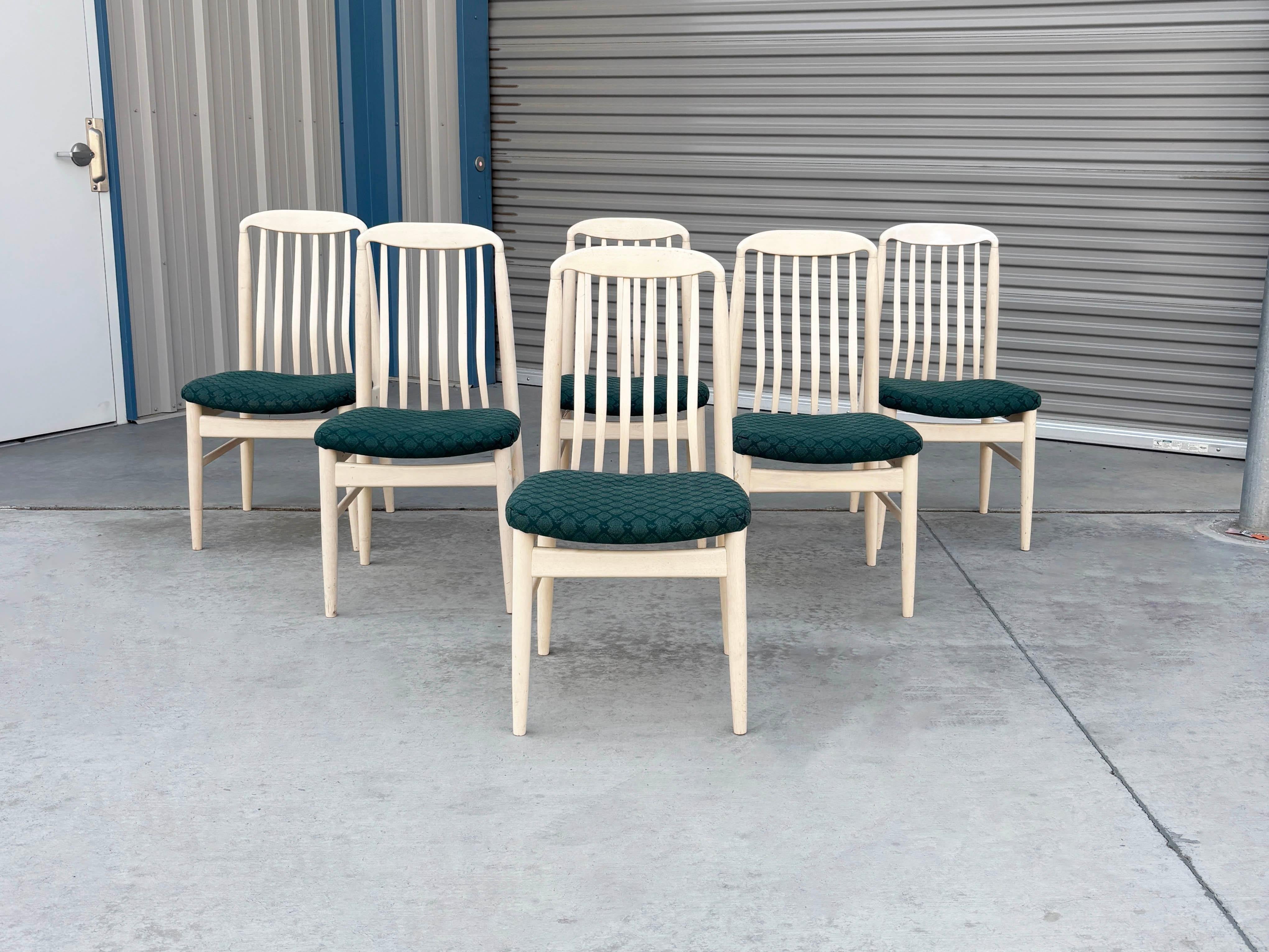 Introducing a stunning set of six mid-century dining chairs, elegantly painted in white. Each chair features six vertical slats, ensuring ample support for you and your guests. The sleek white finish is beautifully complemented by vibrant green