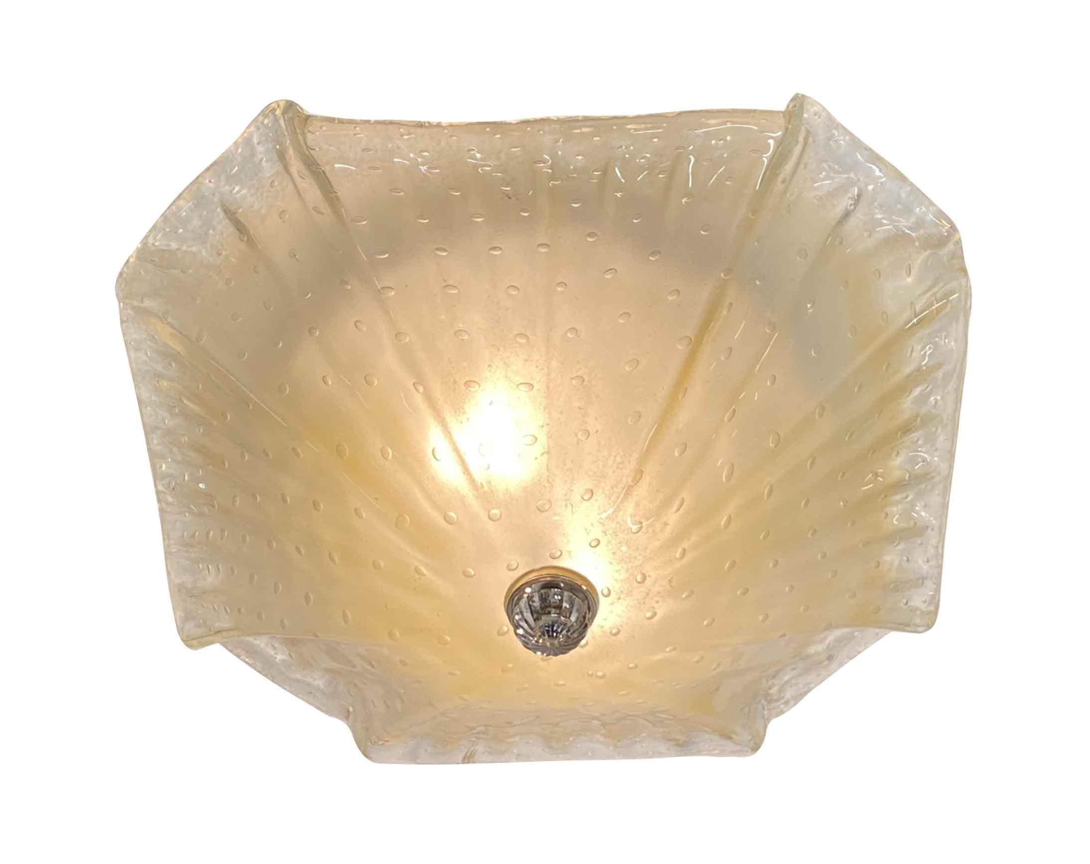 1980s flush mount Mid-Century Modern Italian Murano Lucia light fixture. Partly hand blown and partly molded with ruffled edges. Features tiny delicate bubbles. The glass itself when lit has a subtle peachy yellowish tint. Uses two 60W standard