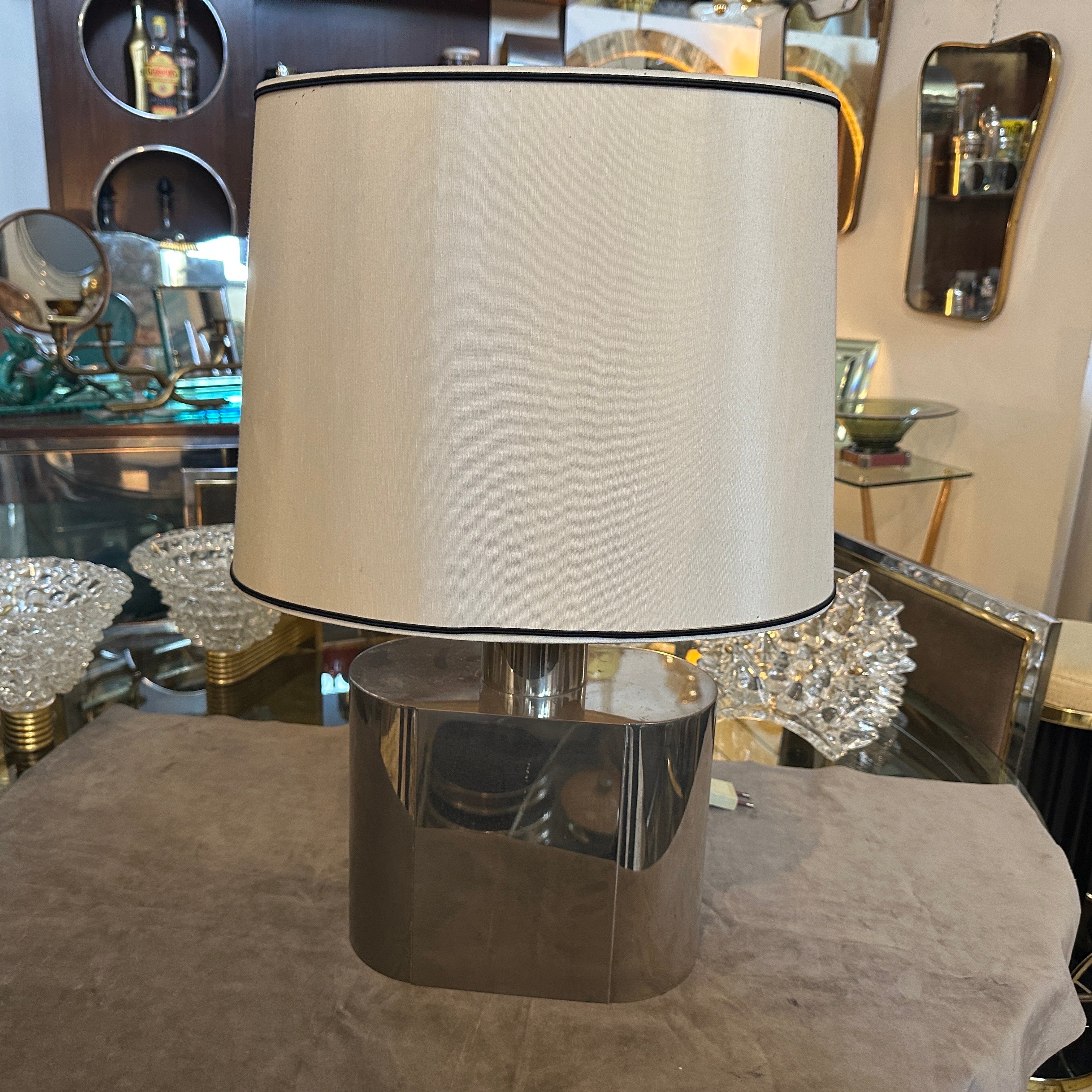 Se trata de una lámpara de mesa ovalada de acero de los años 80 diseñada por Tommaso Barbi, un reputado diseñador italiano conocido por sus creaciones sofisticadas y lujosas. La lámpara tiene una base de acero pulido con una elegante forma ovalada,