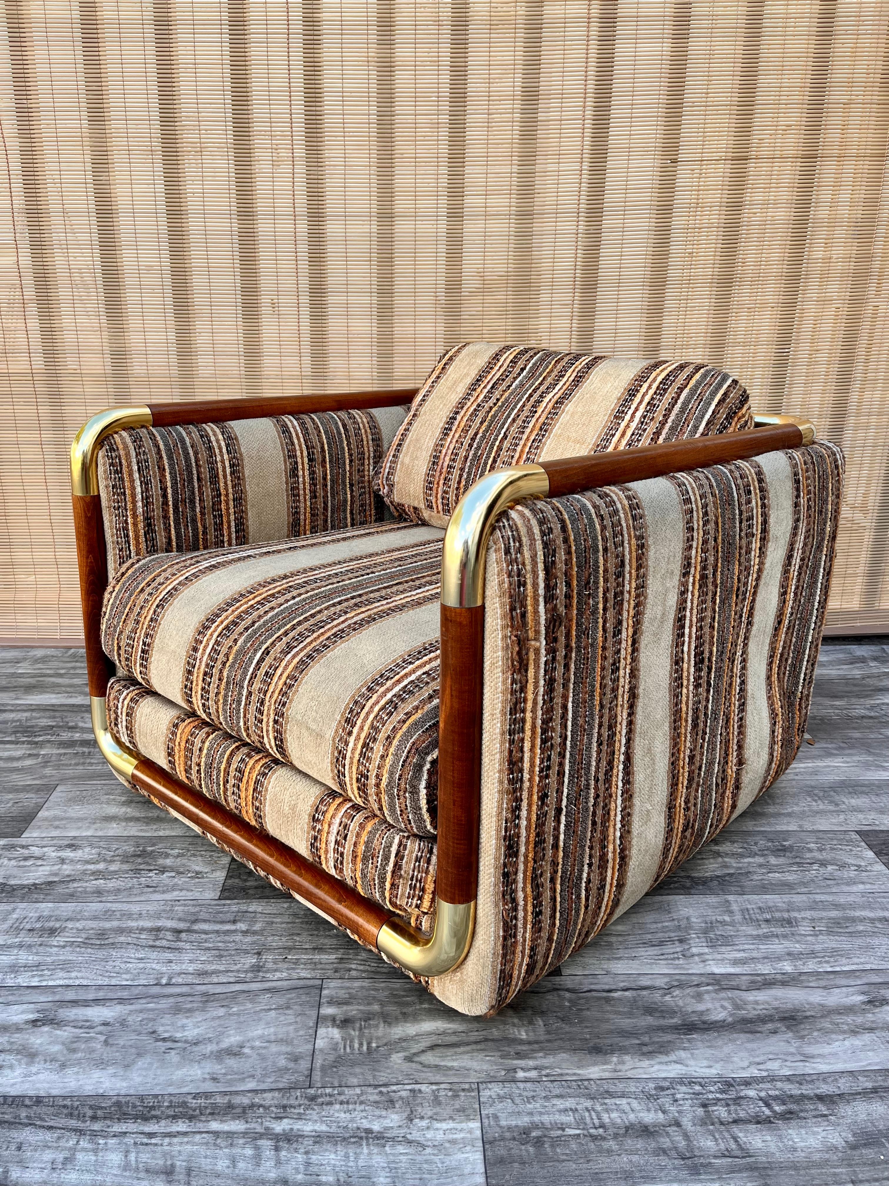 Mid Century Modern Upholstered Cube Club Chair in the Milo Baughman's Style by Schweiger Industries. Manufactured in 1985. 
Features a wood framing with rounded brass trims at corners and the original striped velvety upholstery with removable seat